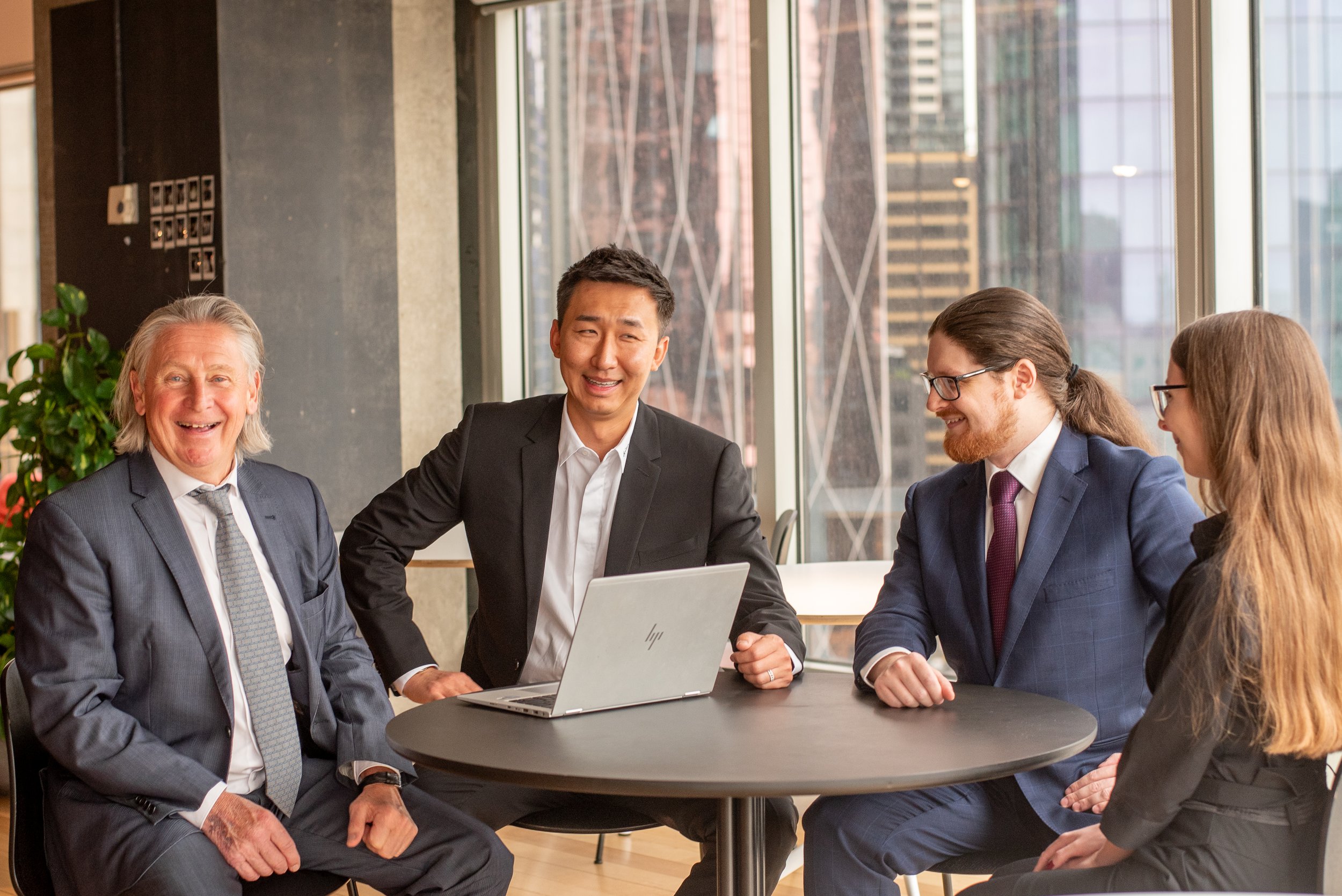smiling team sitting around table conference laptop talking