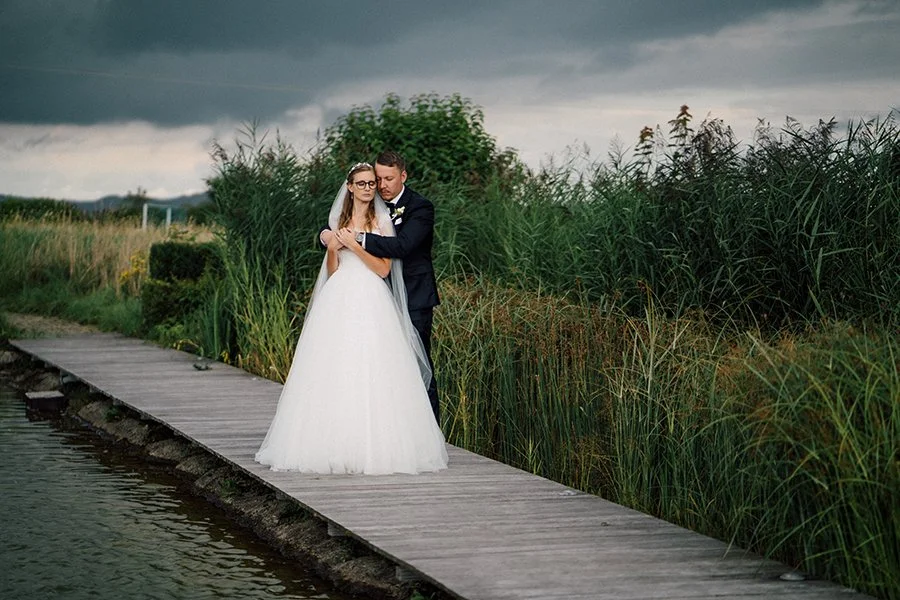 Man steht zusammen auf einem schmalen Steg, umgeben von Natur,
der Himmel schwer &uuml;ber einem und alles f&uuml;hlt sich gleichzeitig ruhig und kraftvoll an.

Fast so, als w&uuml;rde die Welt kurz den Atem anhalten. Und ihr zwei steht einfach mitte