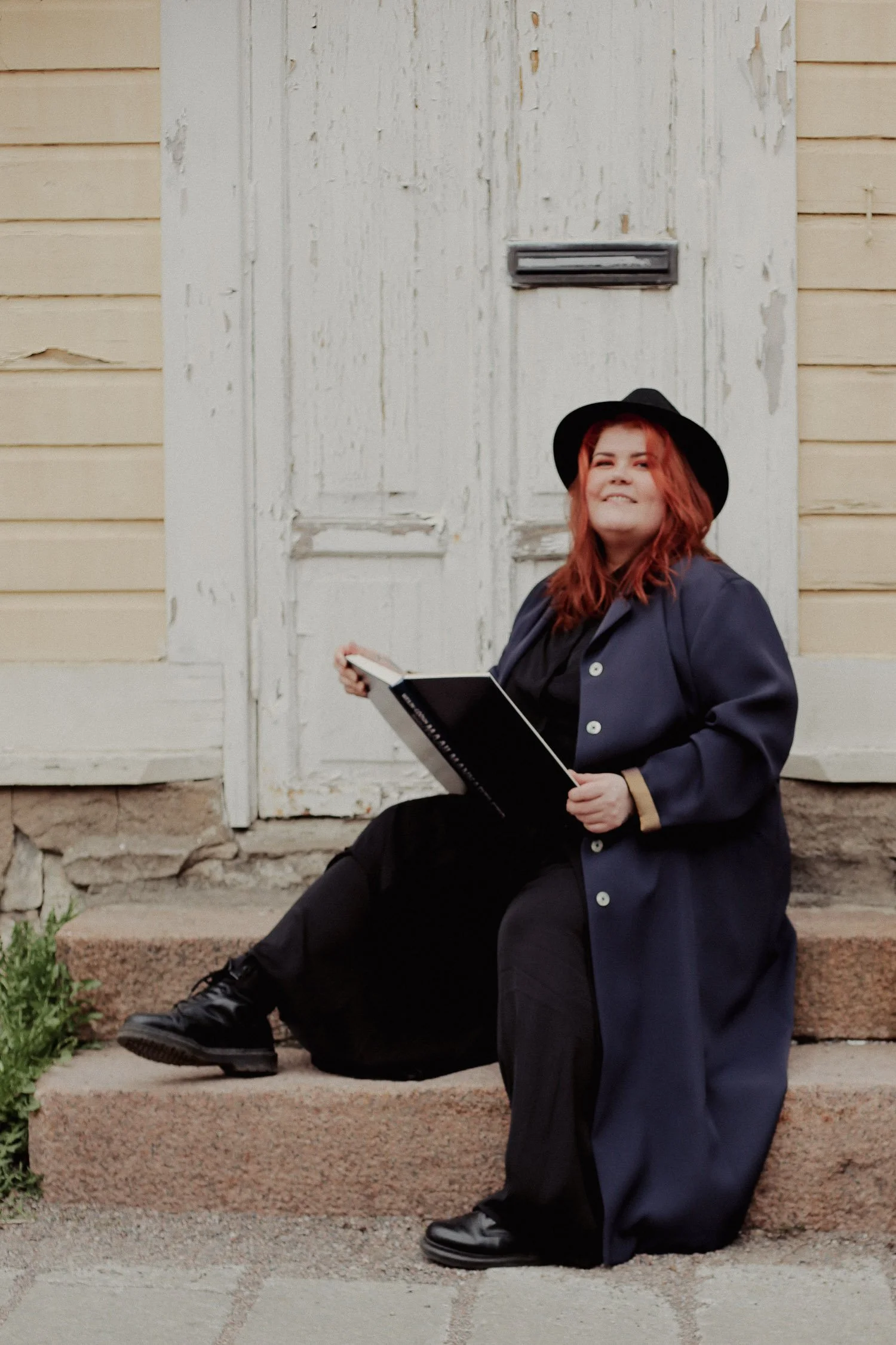 Squarespace nettisivujen tekijä istuu portailla ja pidellen kirjaa.