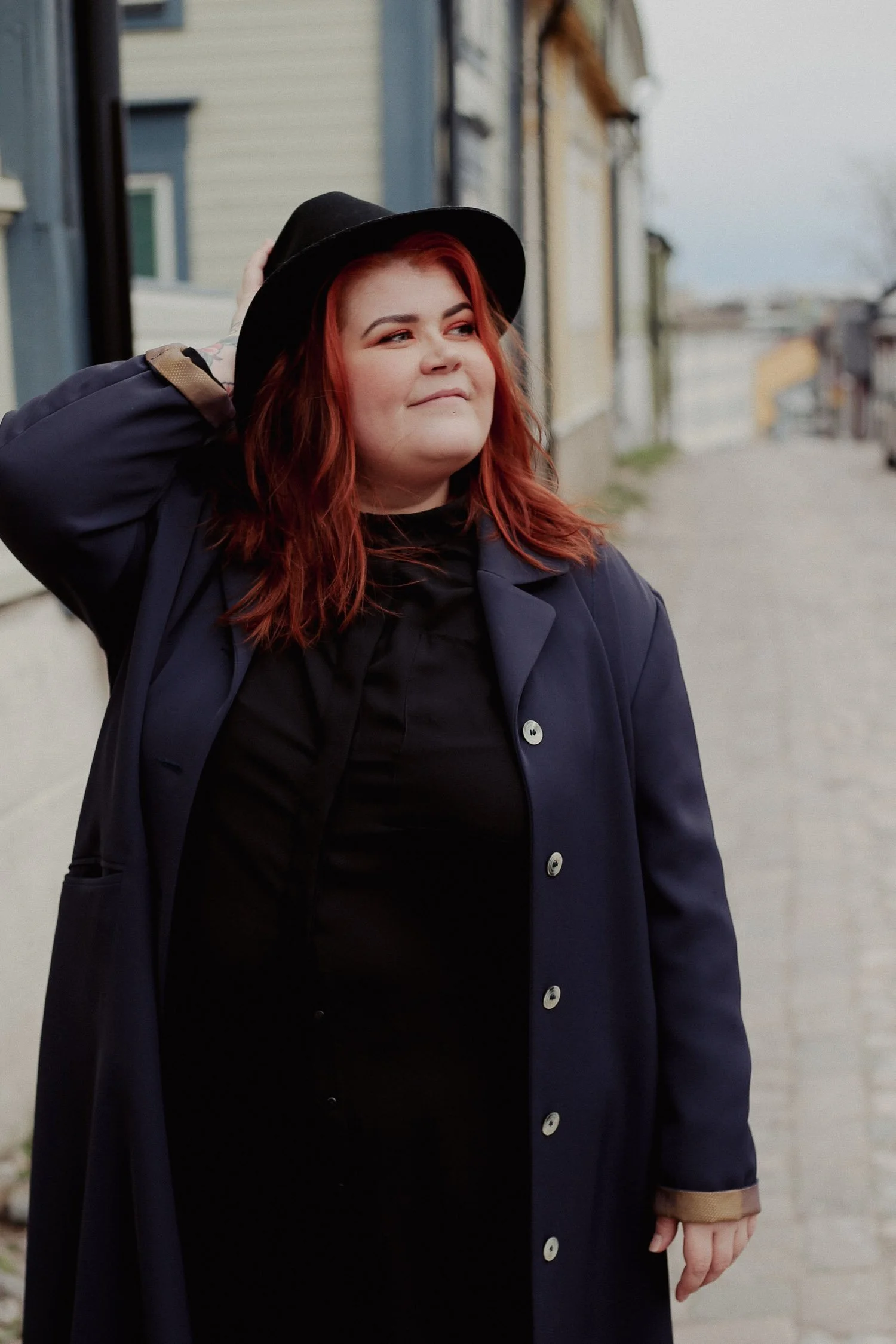 Verkkosivukehittäjä pitelee hatustaan ja hymyilee.