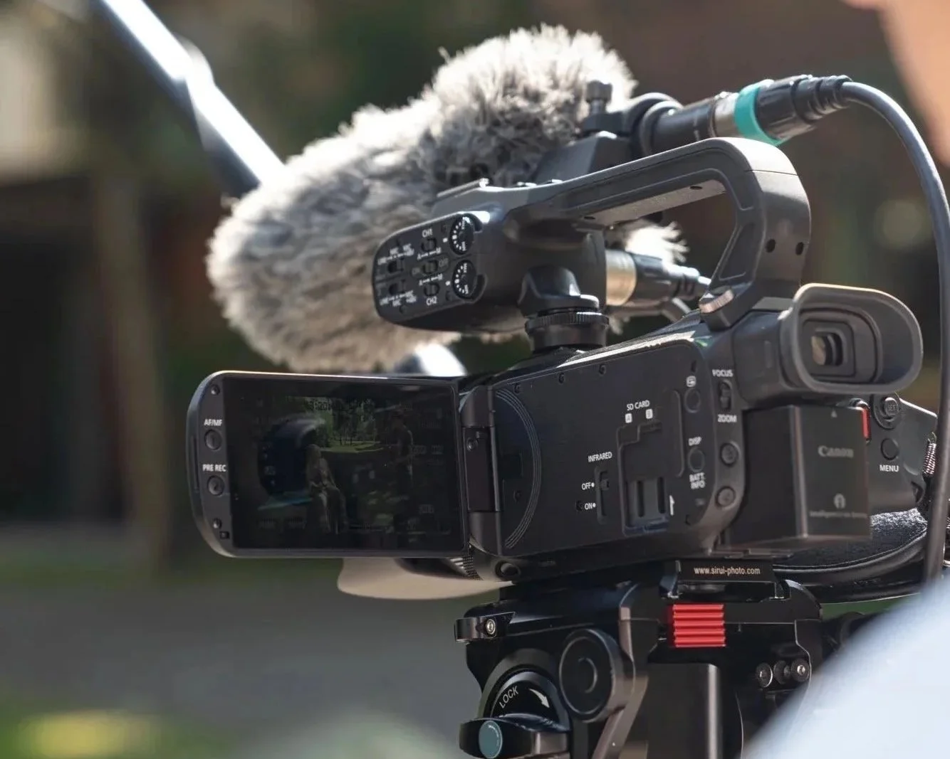 En professionell videokamera med mikrofon riktad mot en utomhusmiljö, troligen för filminspelning.