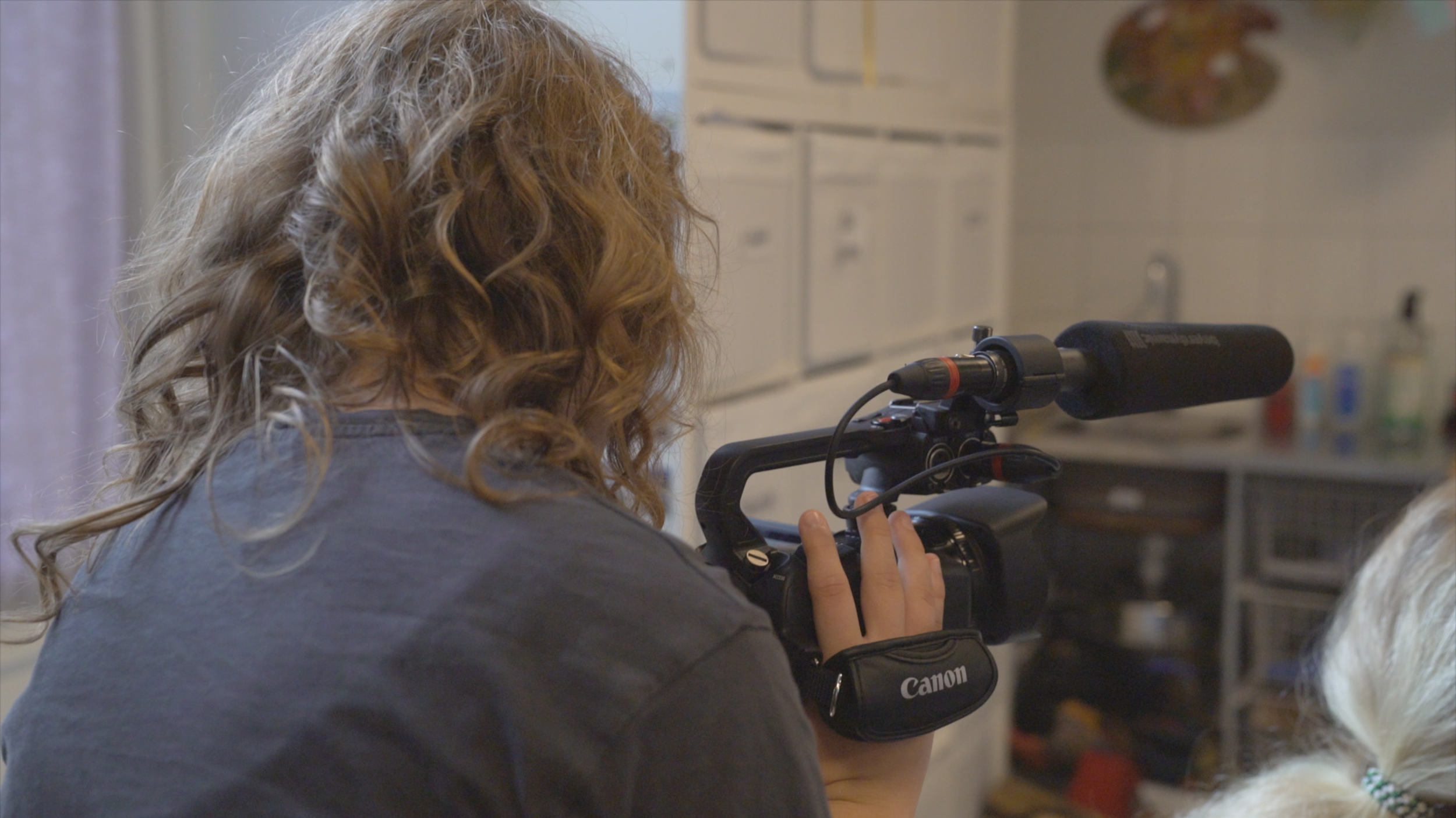 Person med lockigt hår som använder en videokamera i ett laboratorium eller verkstad.