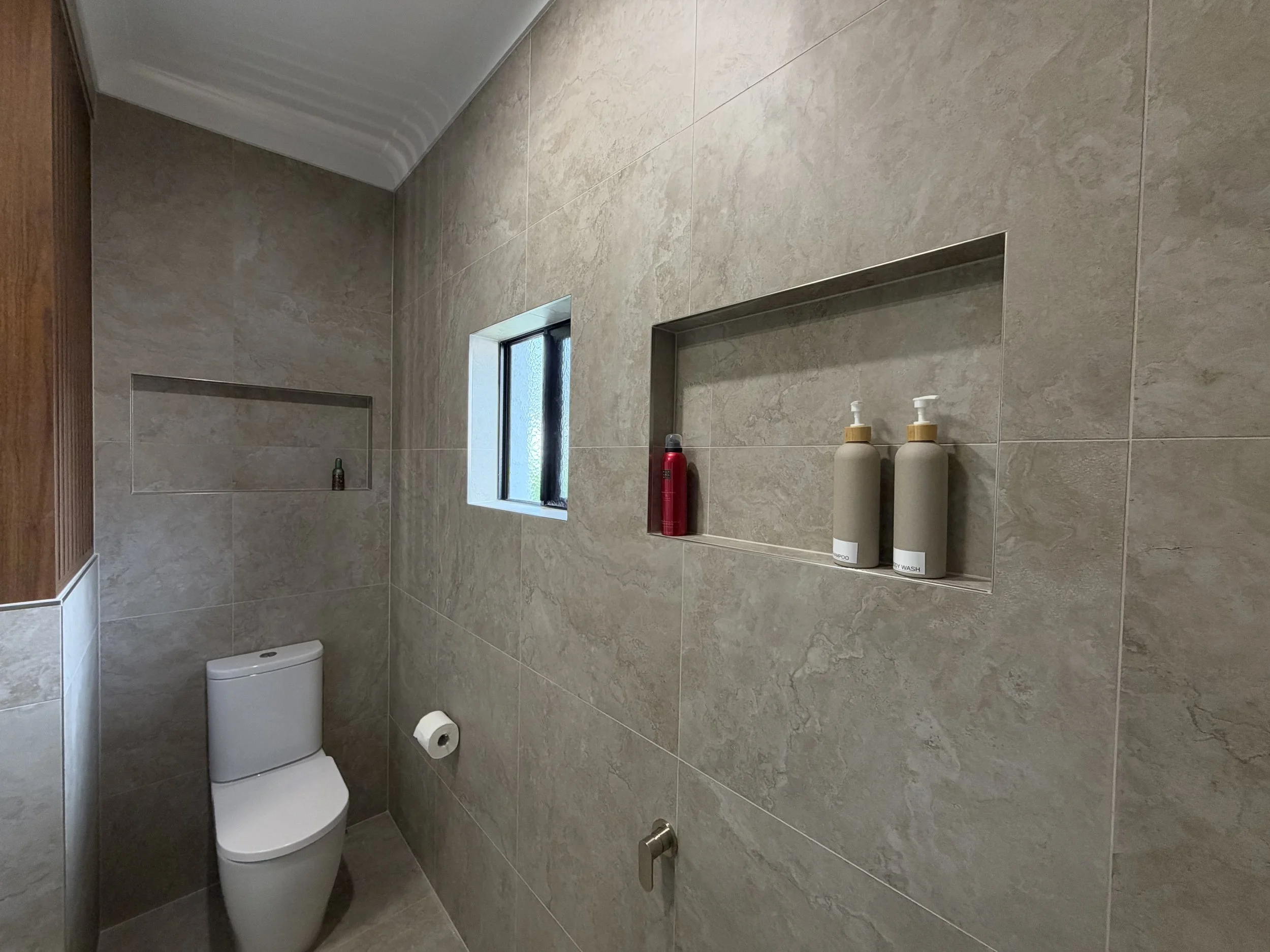 Contemporary bathroom renovation in Wellington Point featuring a recessed shower niche and large-format stone-look tiles.