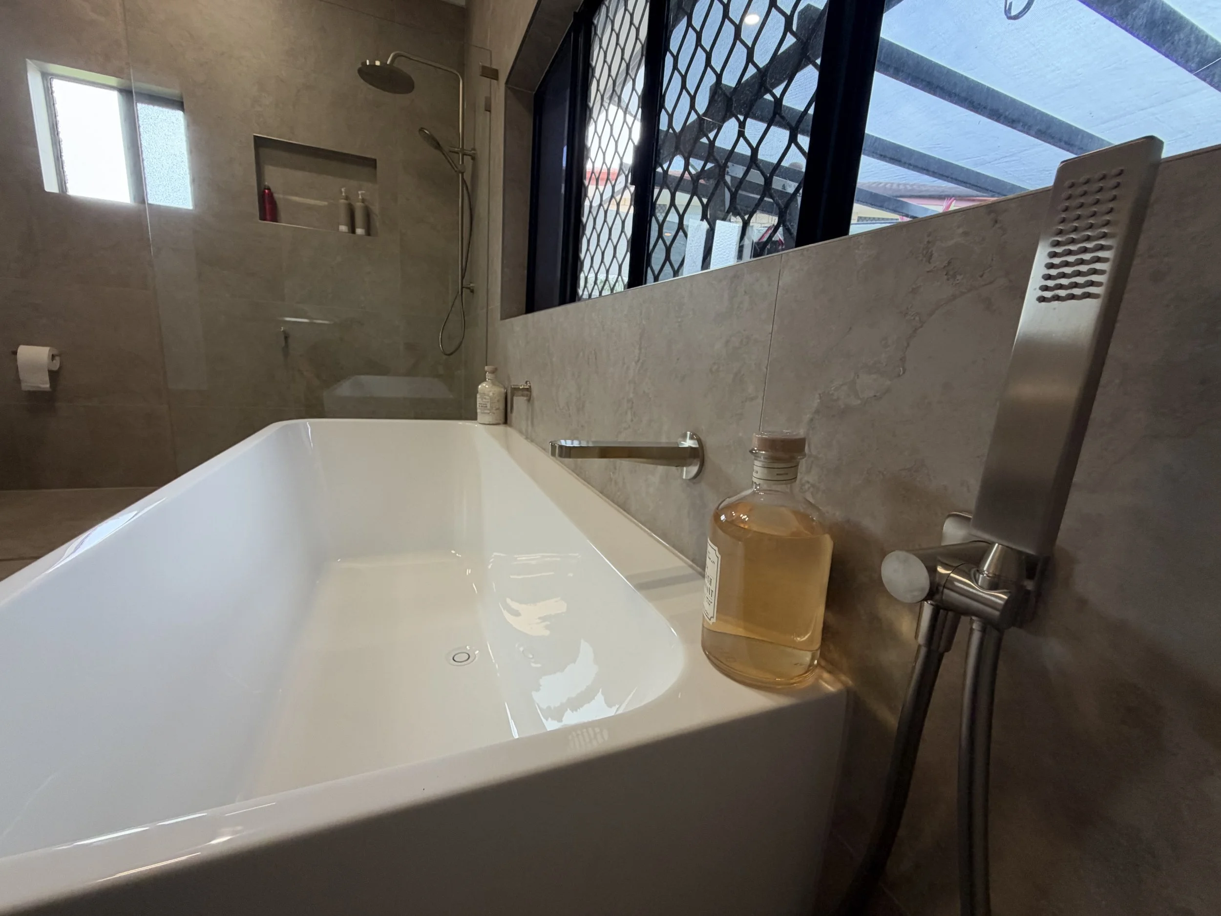 Freestanding Posh Domaine bathtub with brushed nickel Mizu Soothe tapware and Lucca Crosscut Natural bathroom tiles.