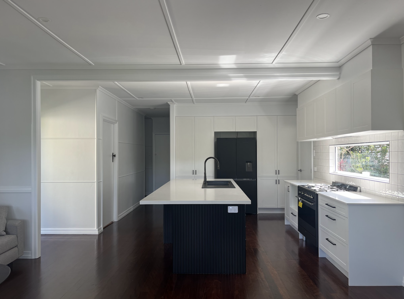 Modern kitchen renovation in Coorparoo featuring white shaker cabinetry, black island bench and polished timber floors.