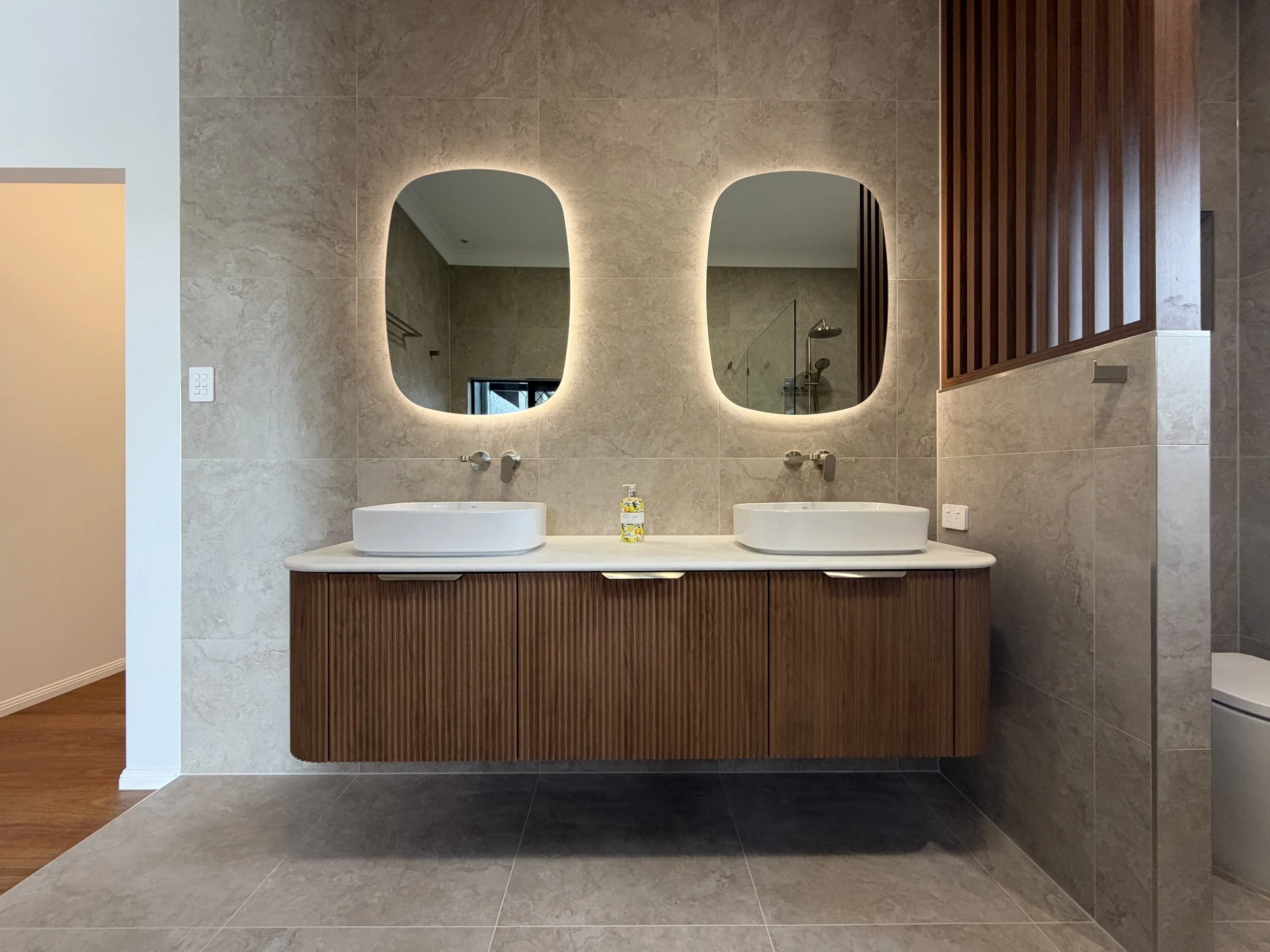 Custom Kado Neue fluted double vanity with Roca basins, illuminated Kado Aspect mirrors and brushed nickel Mizu tapware.