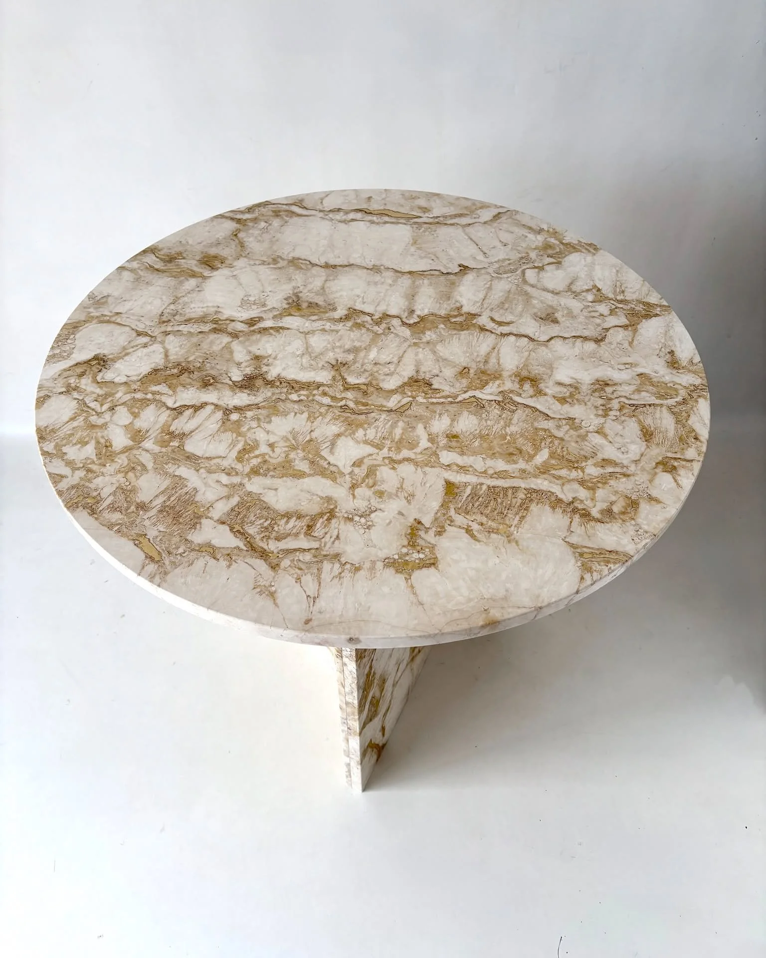 A one-off table designed and handcrafted from reclaimed Rapolano travertine offcuts. The circular top is balanced by a central overlapping base with sculpted reeded details.

Each piece of salvaged stone carefully selected and composed to celebrate t
