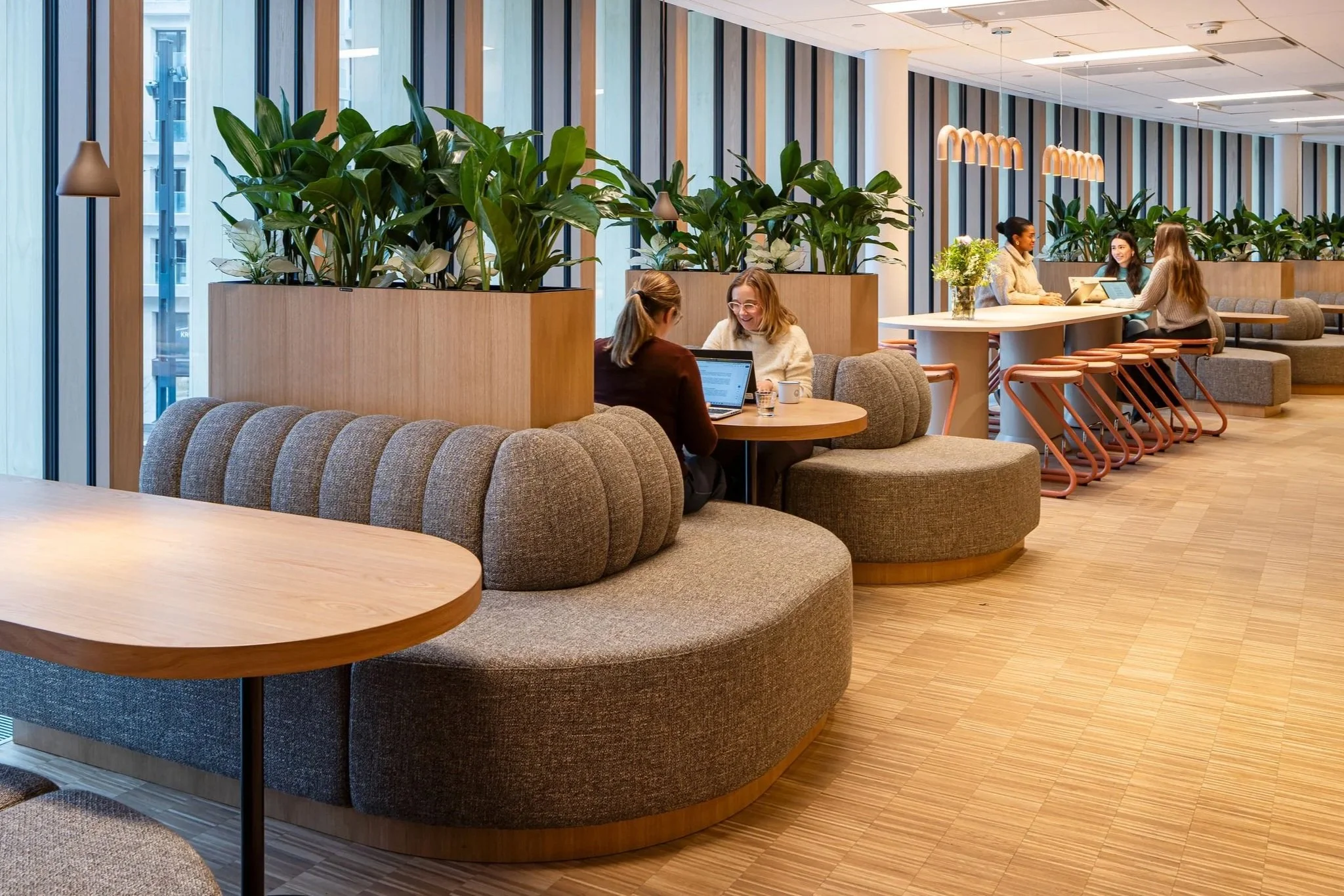 Moderna café med växter, sittplatser och personer som arbetar på laptops.