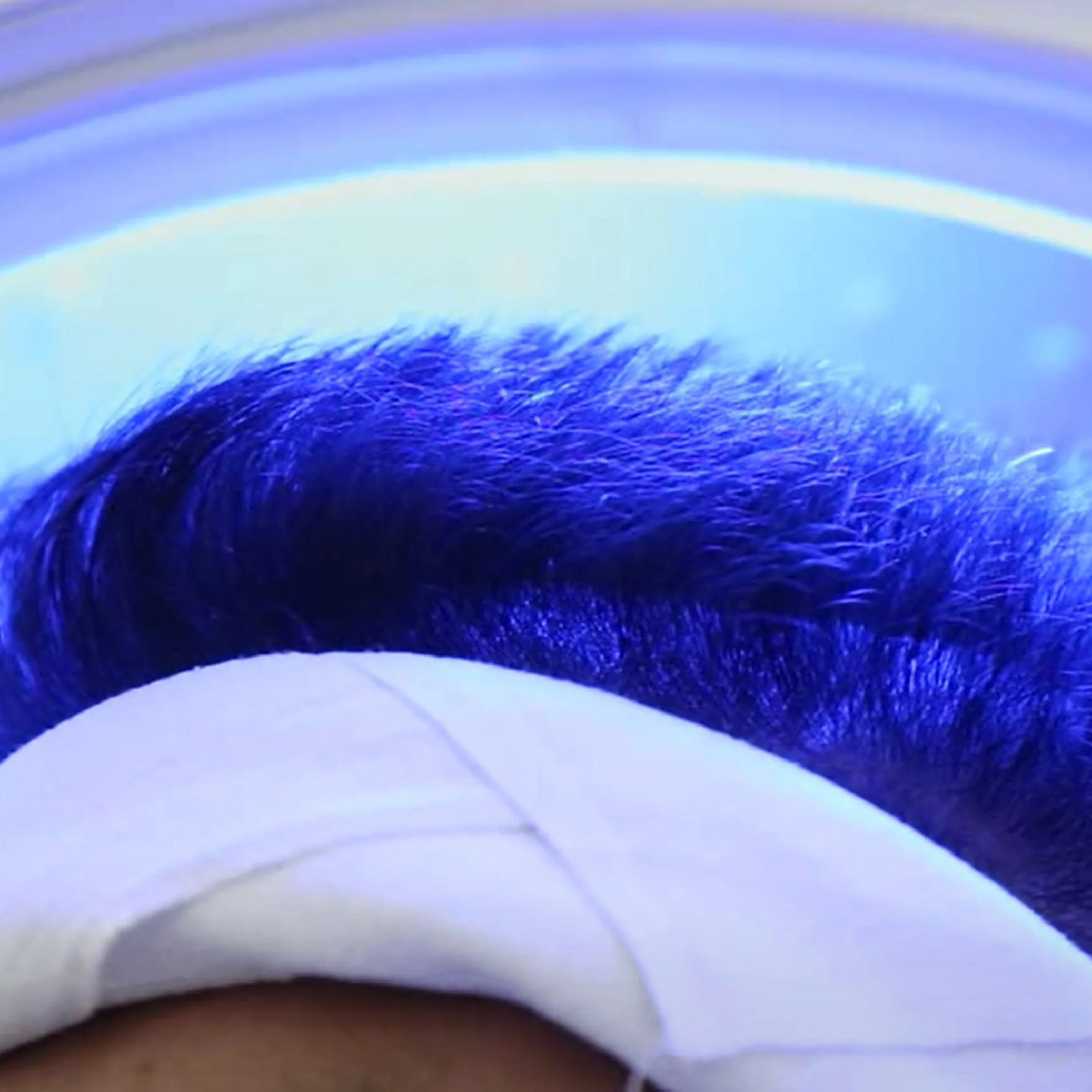 Close-up of a person's eye with eye shadow, wearing a white face mask.