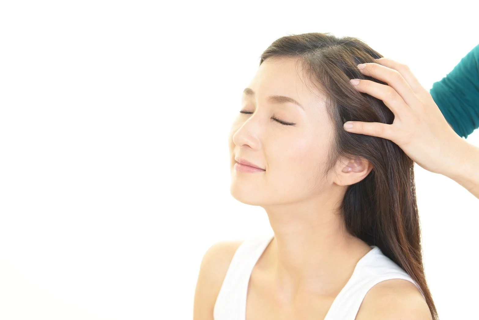 Woman receiving a head massage with closed eyes and a peaceful expression, on a white background.