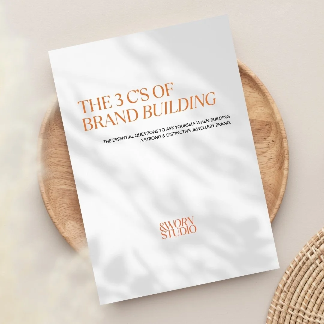 A printed booklet titled 'The 3 C's of Brand Building' resting on a wooden plate, with a wicker basket partially visible in the lower right corner.