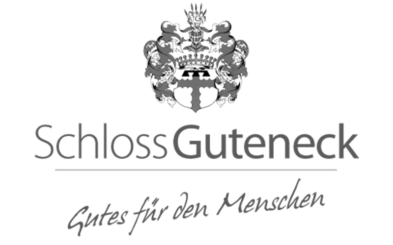 Das Bild zeigt ein Wappen mit einer Krone, einem Schild mit einem Kreuz und einem Wappenbanner darunter.