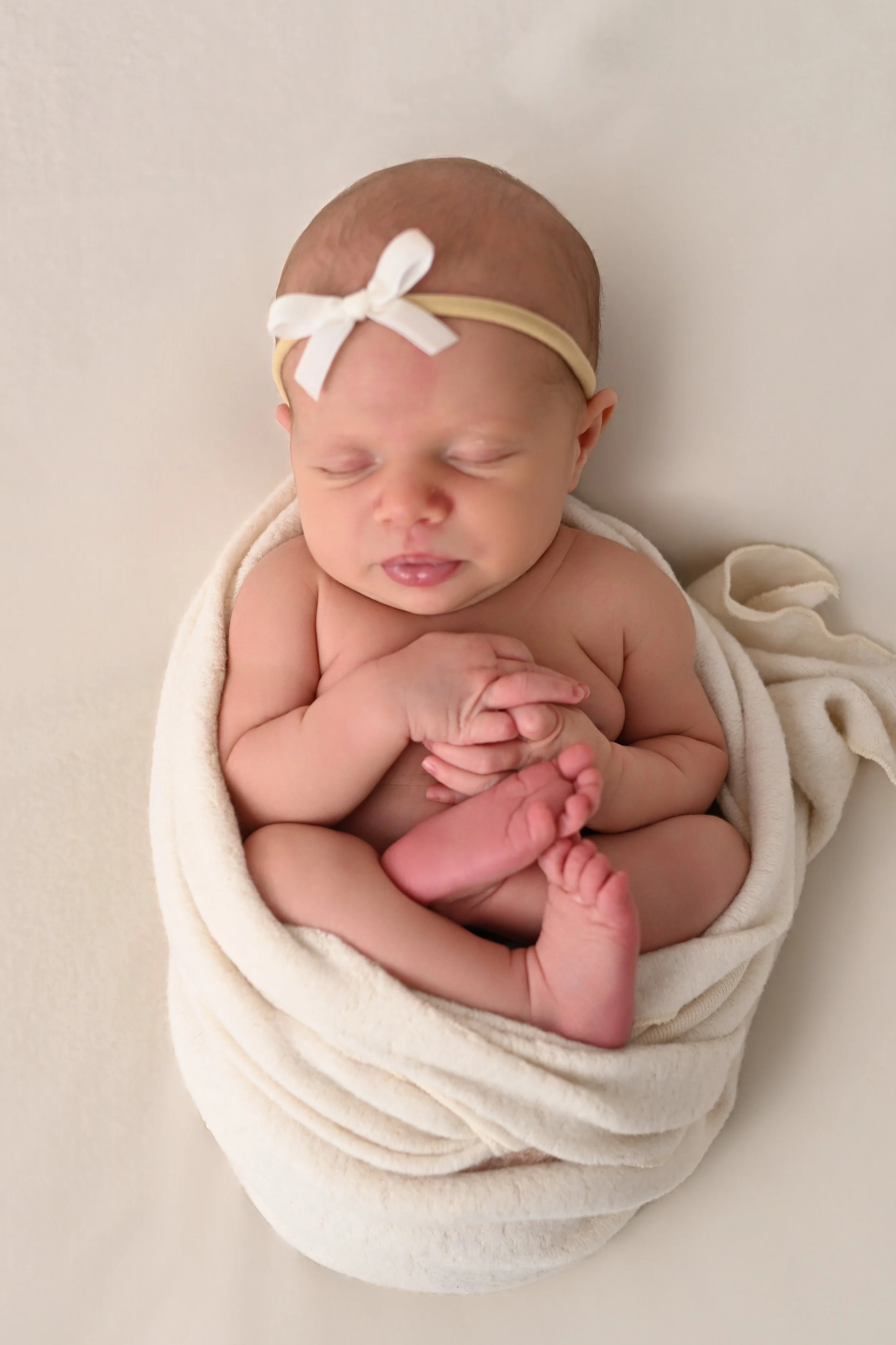 Newborn baby posed in neutral wrap during studio photography session