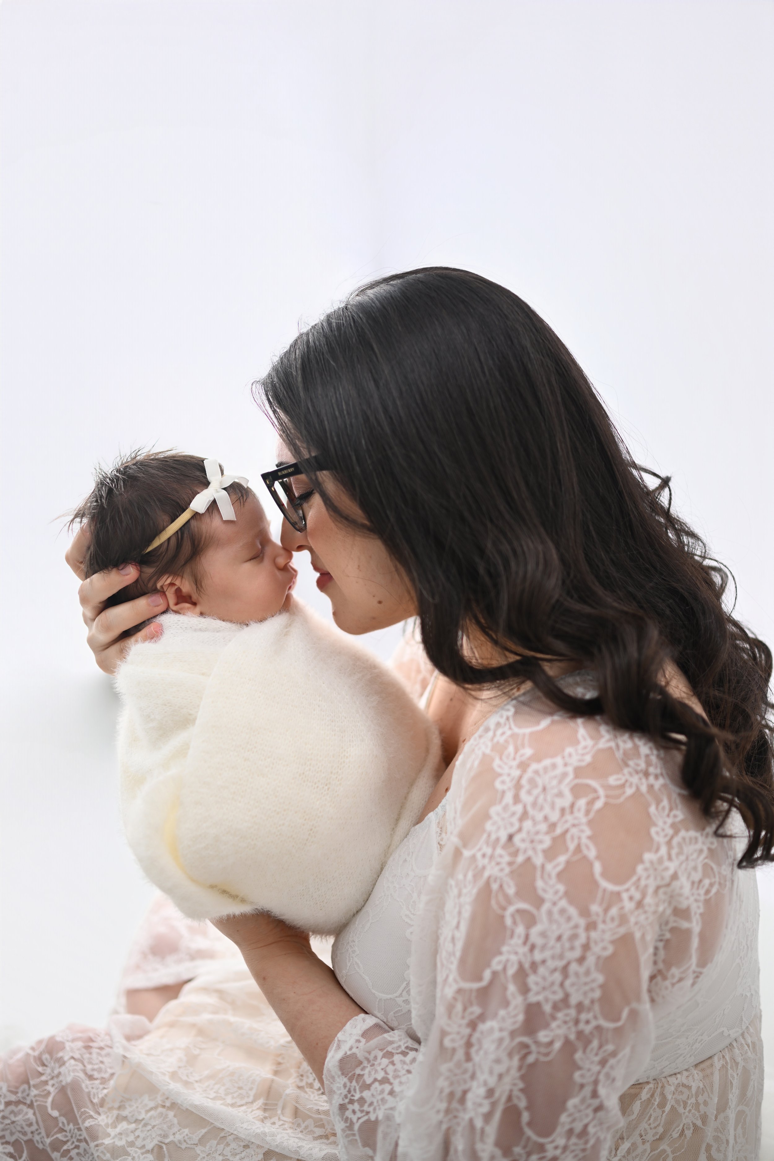 Mother kissing her newborn baby during a newborn photography session at Beachside Portraits in Satellite Beach, Floriday
