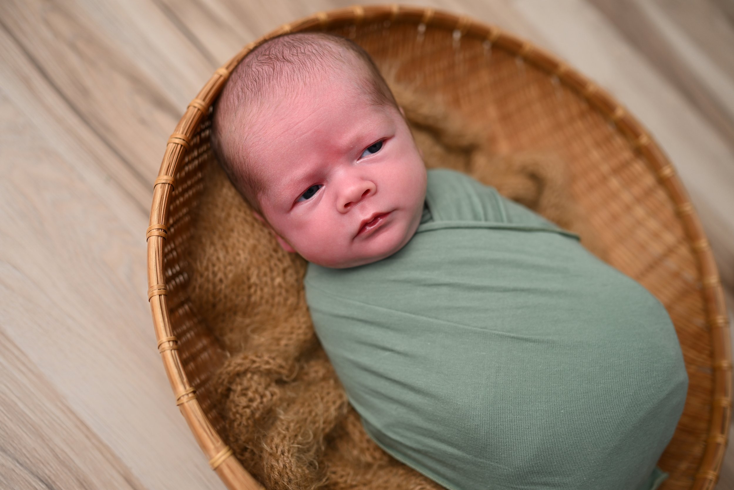 Newborn baby in green swaddle during studio photography session in Satellite Beach