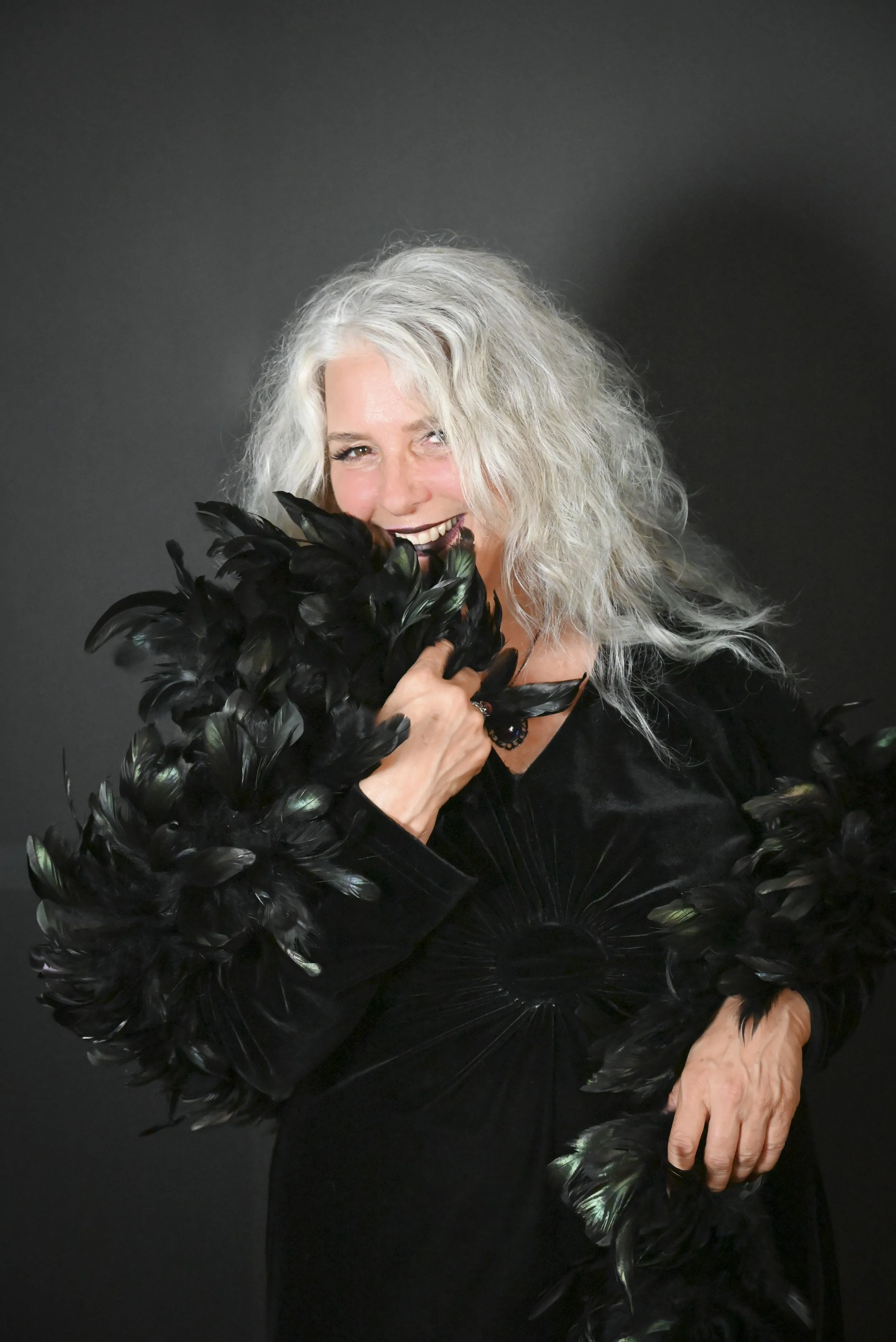 A portrait of a smiling woman looking at the camera with a feather boa.