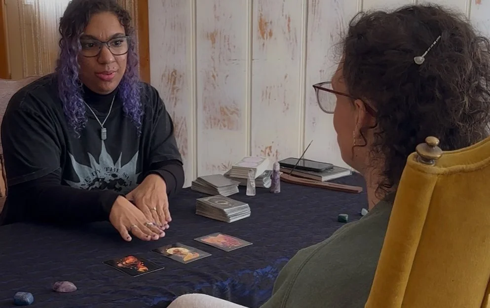 A photo of a tarot card reader doing a reading as part of the Wicked Wise Women Project.