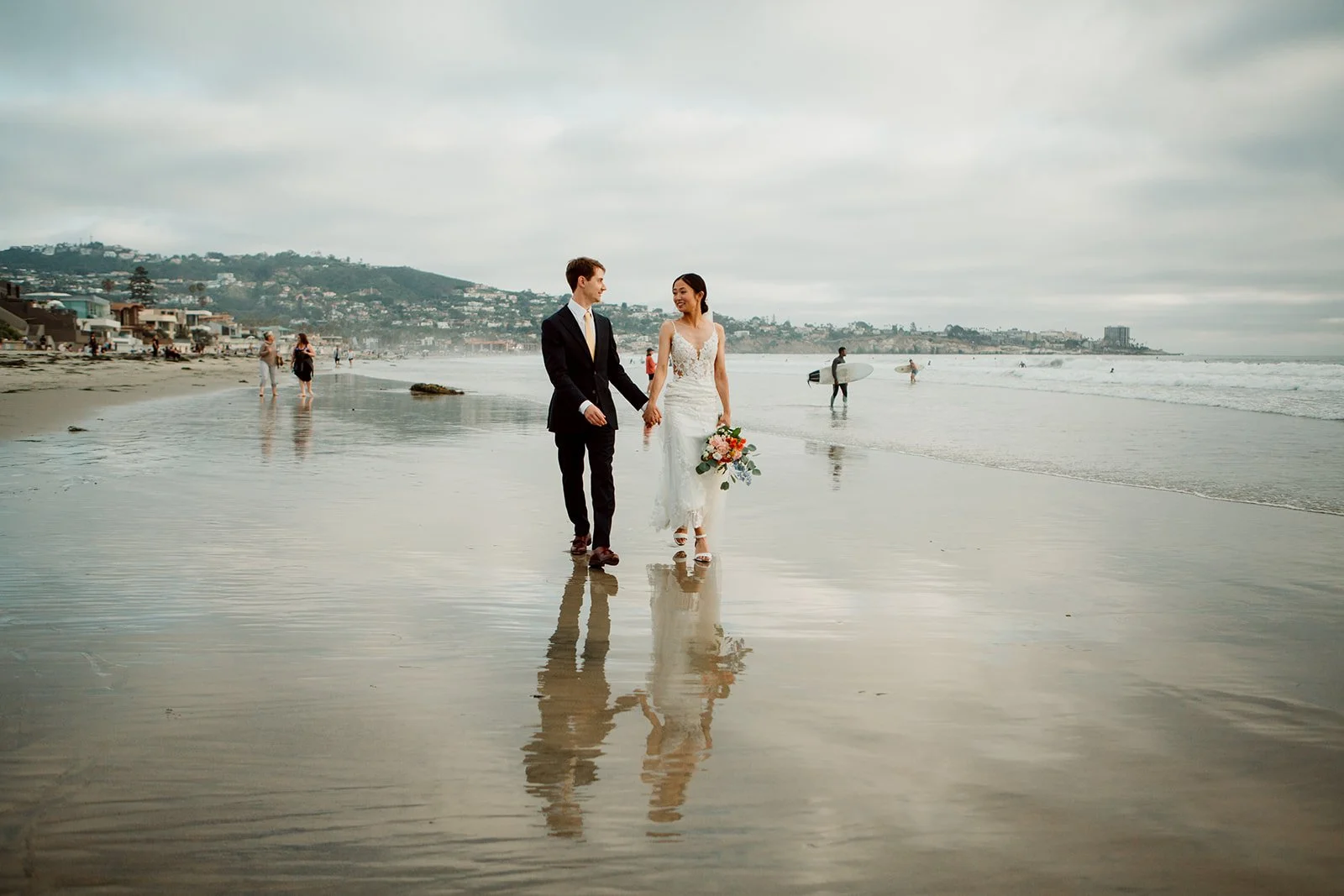 Couple walks beach at Scripps Forum after their wedding ceremony.