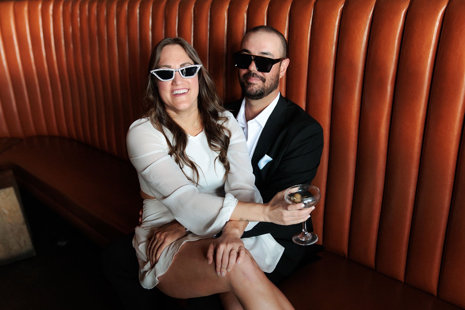Fun candid photo of a bride to be sitting in her boyfriend's lap laughing for their engagement shoot.