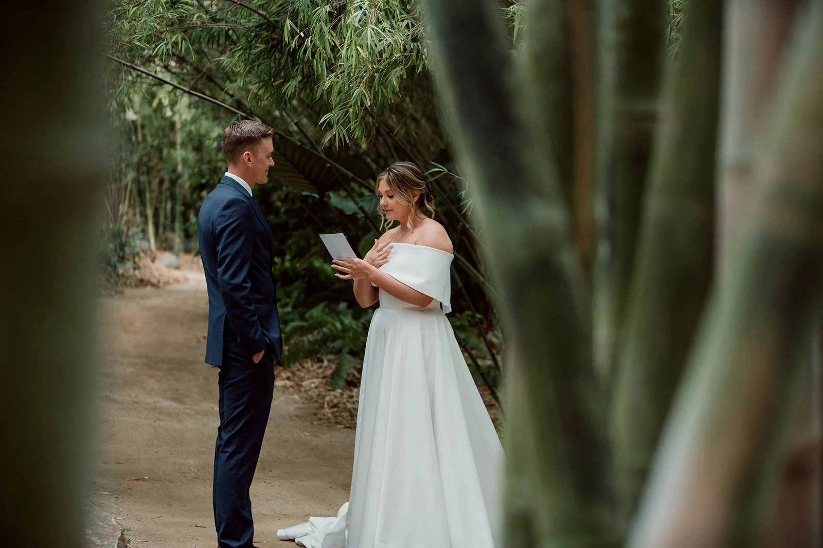 San Diego Botanic garden candid wedding moment shows a couple reading their vows in the bamboo forest.