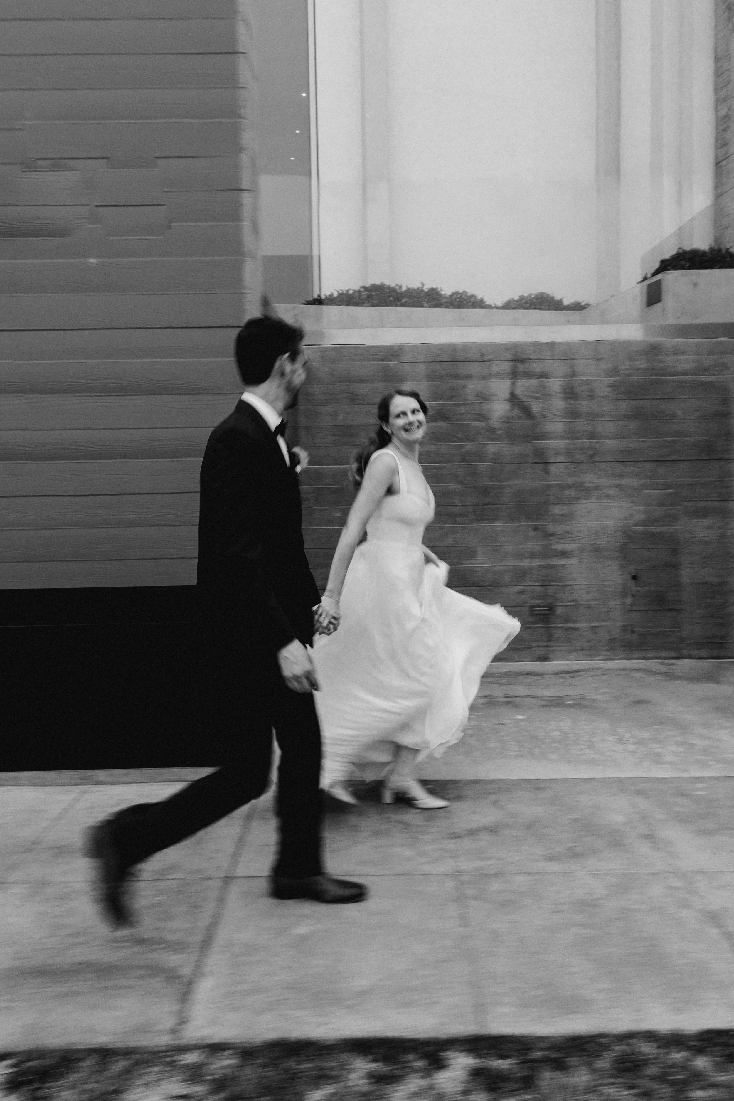 Bride and groom laugh while walking hand in hand for their La Jolla wedding ceremony in San Diego,