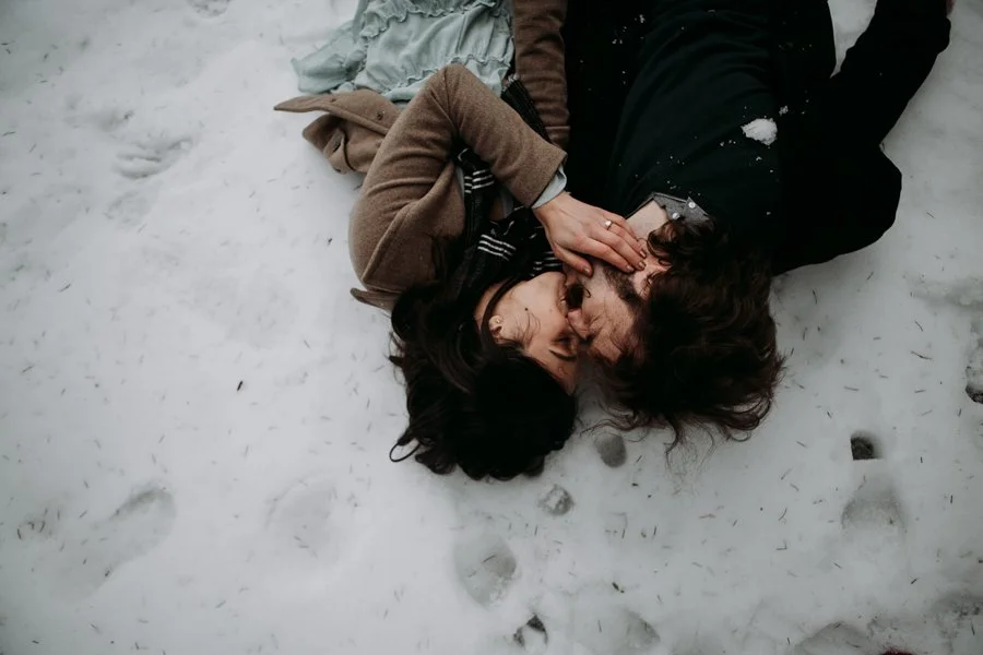 Couple kisses in snow for their engagement photoshoot.