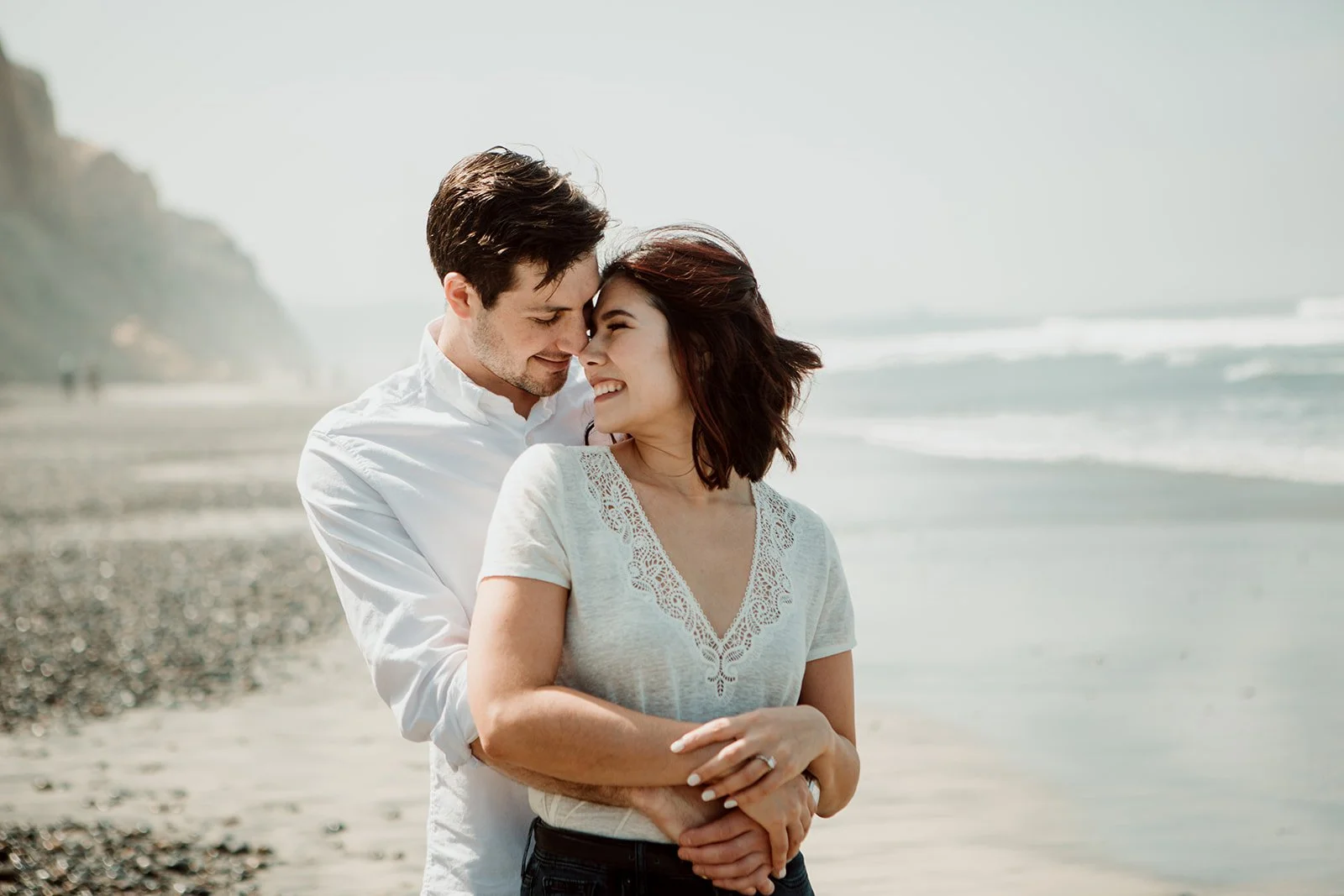 Man holds his fiancée and smiles after their surprise San Diego wedding proposal photo shoot in Torrey Pines.