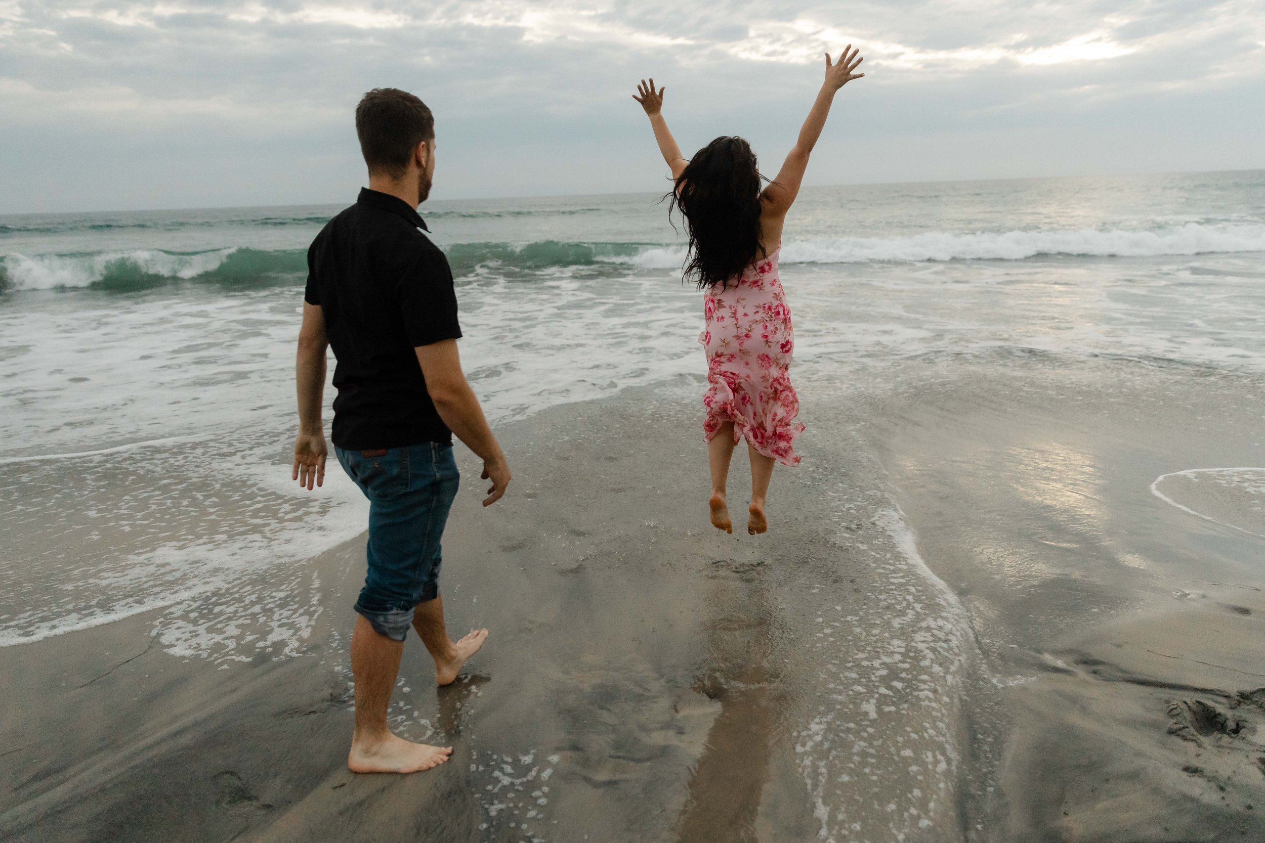 Couple joyfully runs into water at their Coronado beach engagement photoshoot.