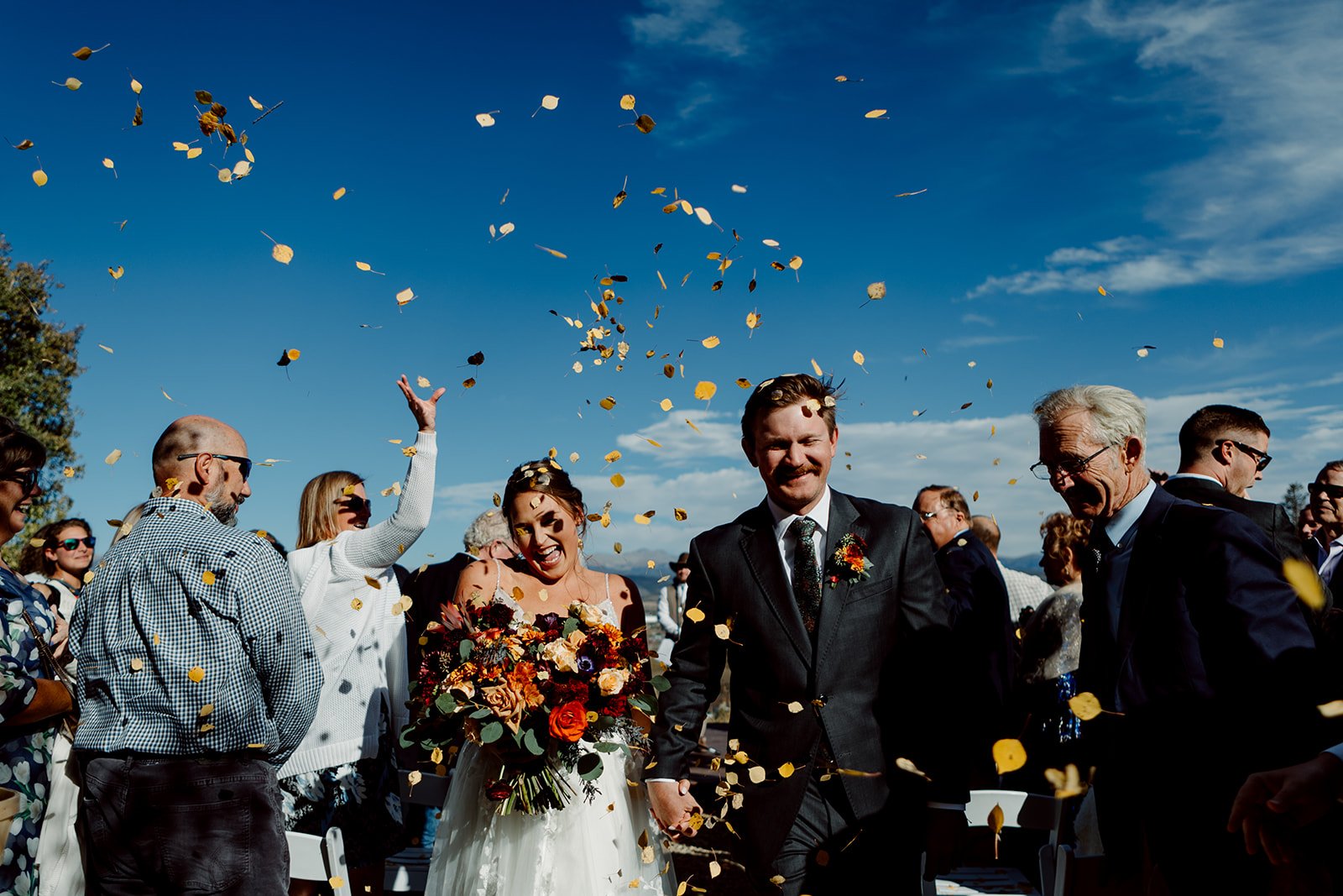 San Diego wedding ceremony photograph of guests throwing petals towards a laughing bride and groom as they exit their wedding ceremony.