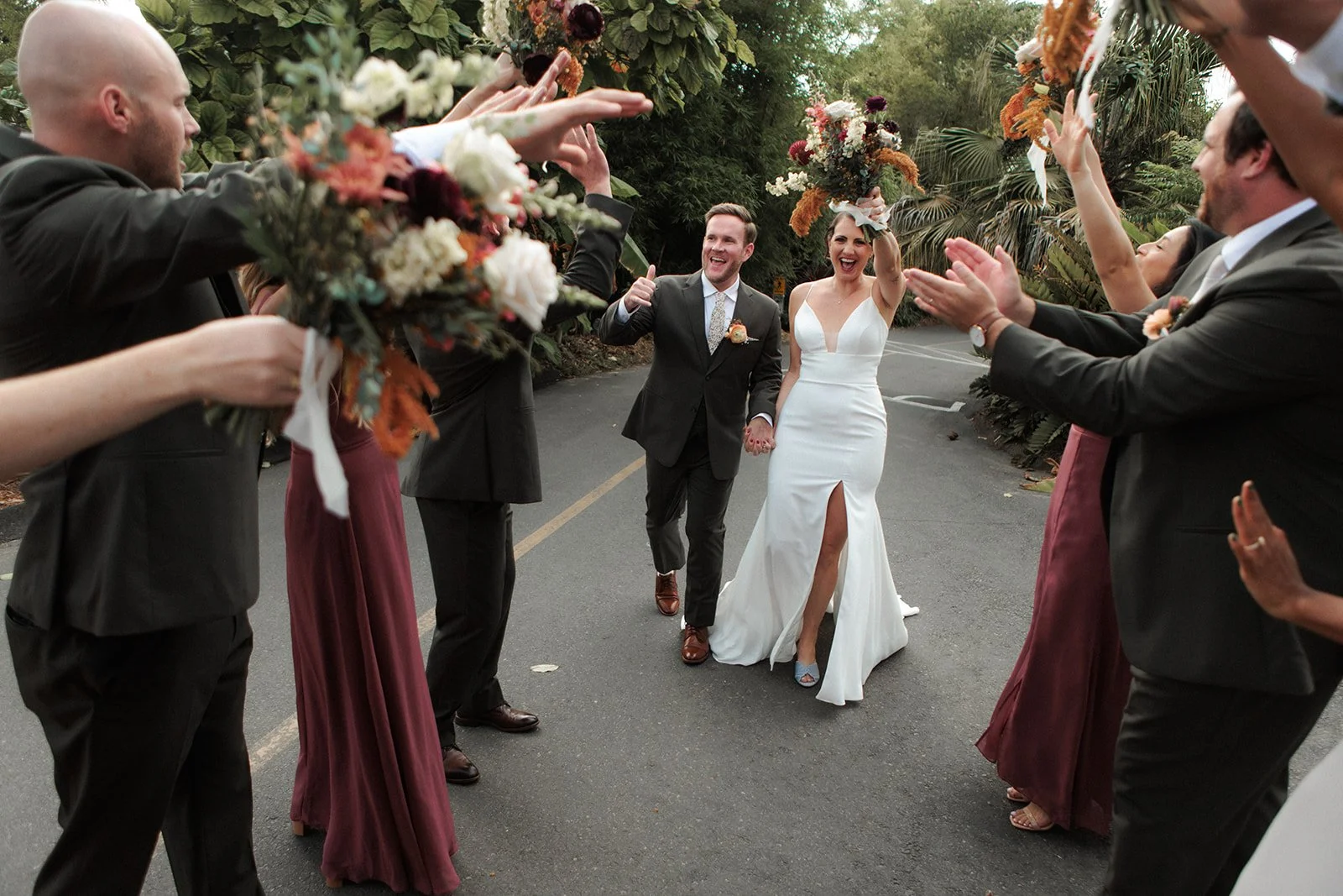 Bride and groom celebrate their wedding with walking past their friends that are clapping at at San Diego Botanic Garden.