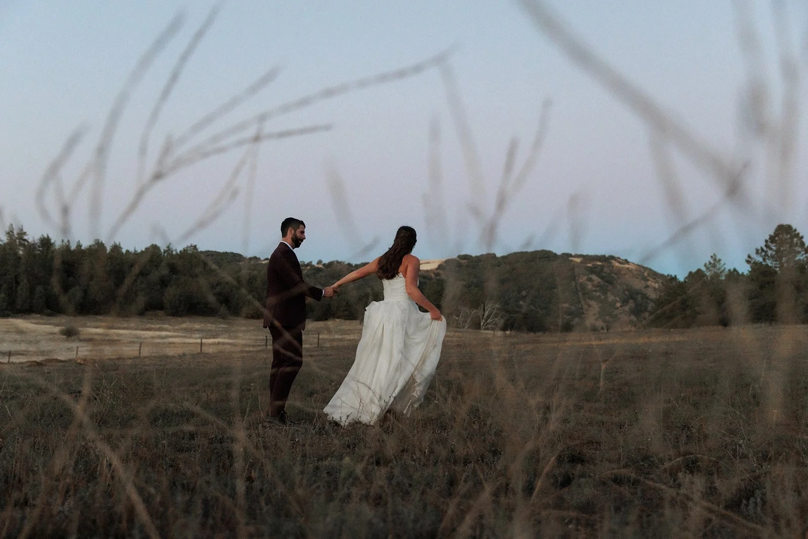 Candid photo of couple walking through a beautiful field at sunset for their San Diego wedding in Julian.