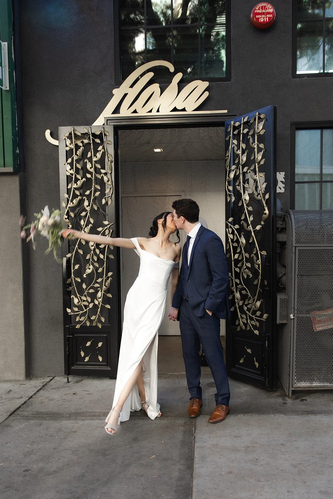Bride and groom kiss outside front entrance at their wedding at Flora the venue in downtown San Diego.