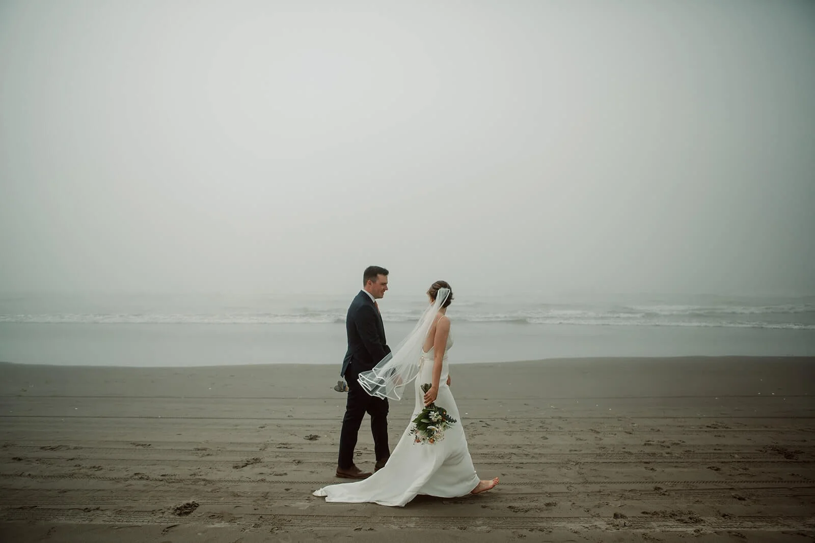Bride and groom walk on Coronado beach for their wedding.