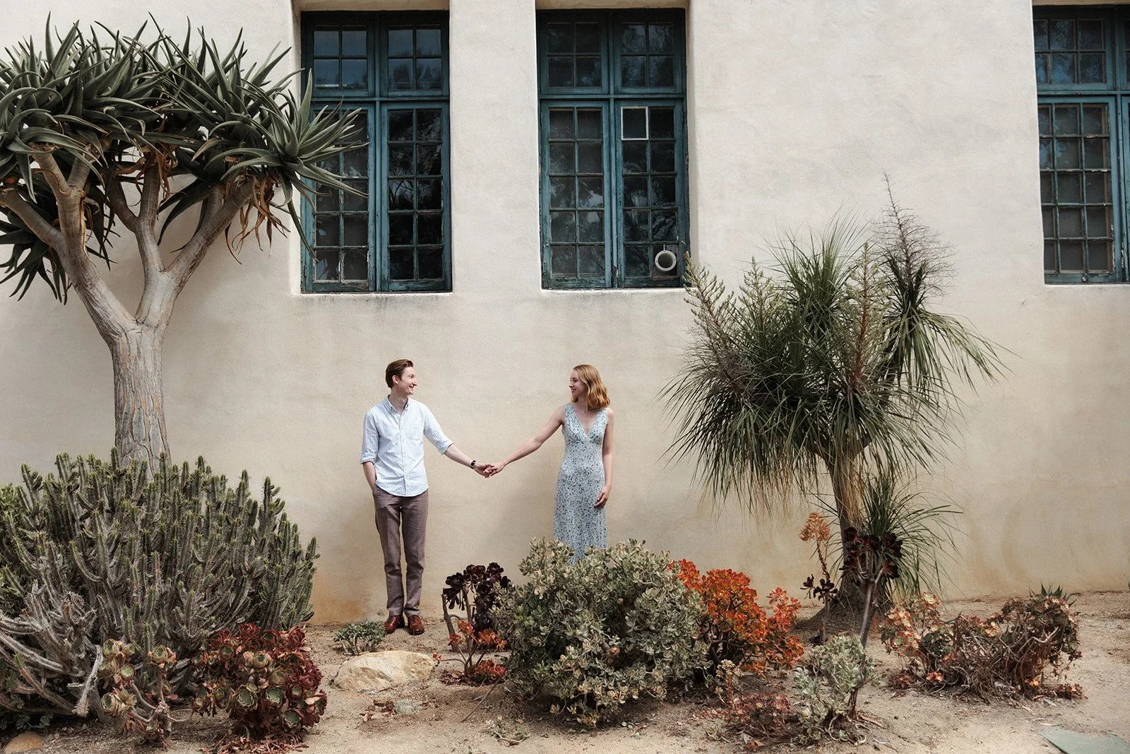 Couple stands holding hands for their proposal and engagement photos in Balboa Park.