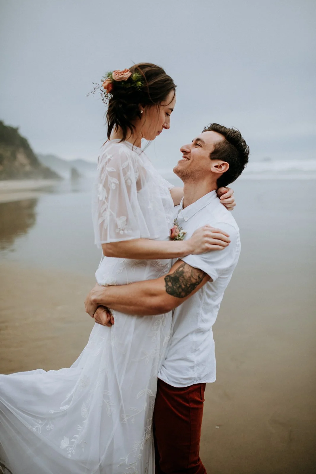 Groom lifts bride on a beach for their San Diego wedding.