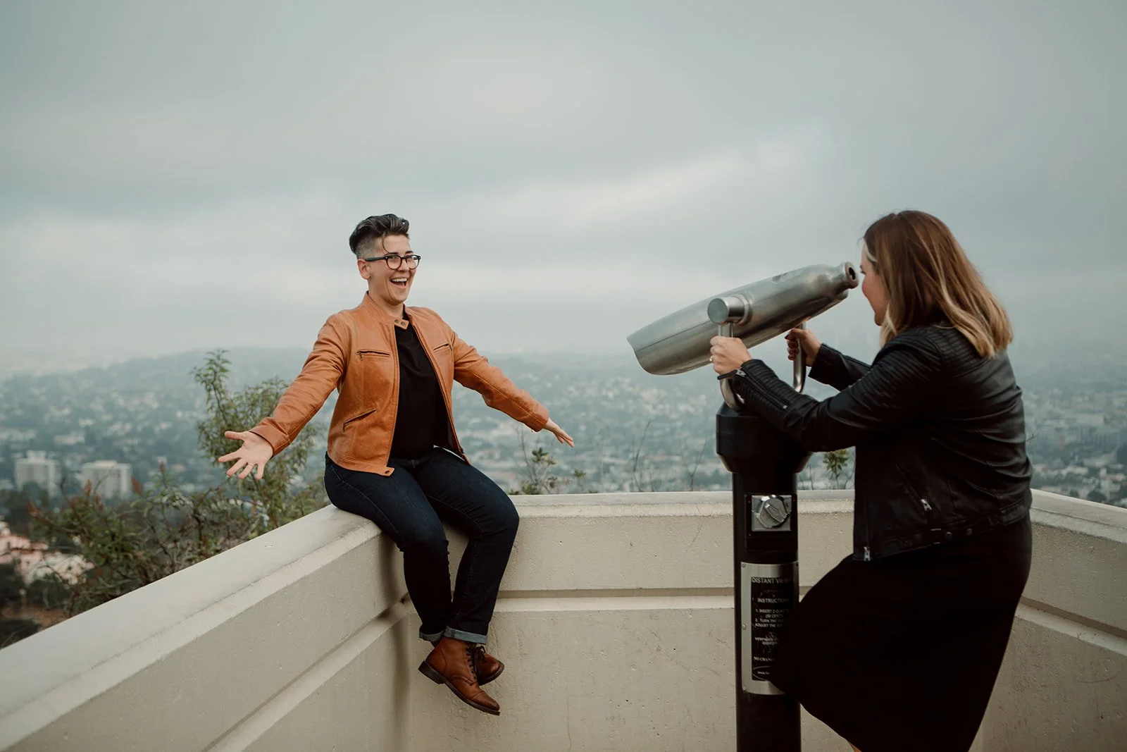 Playful engagement photo of a couple on an overlook.