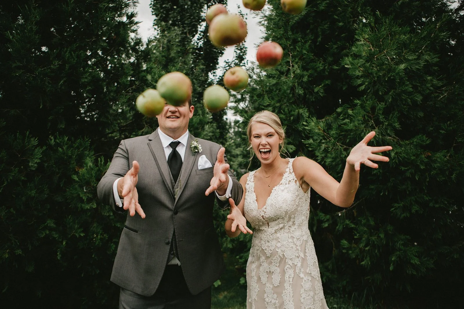 Bride and groom toss apples at the camera for their playful San Diego wedding photography session.