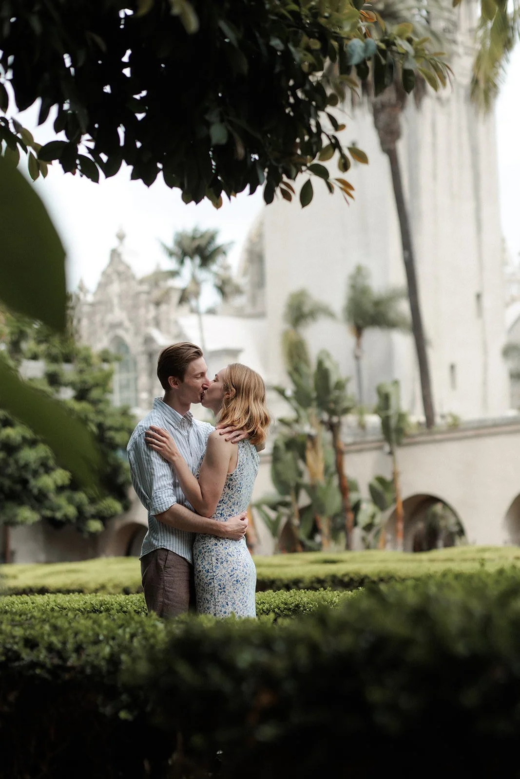 Man and woman kiss after he proposes to her in Balboa Park.