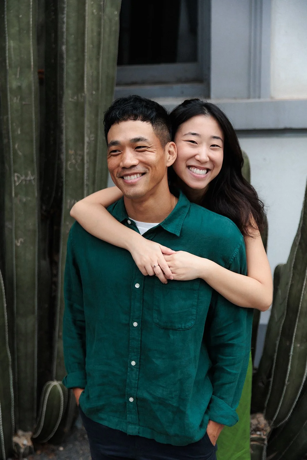 Couple embraces and smiles candidly during their San Diego engagement photo session.