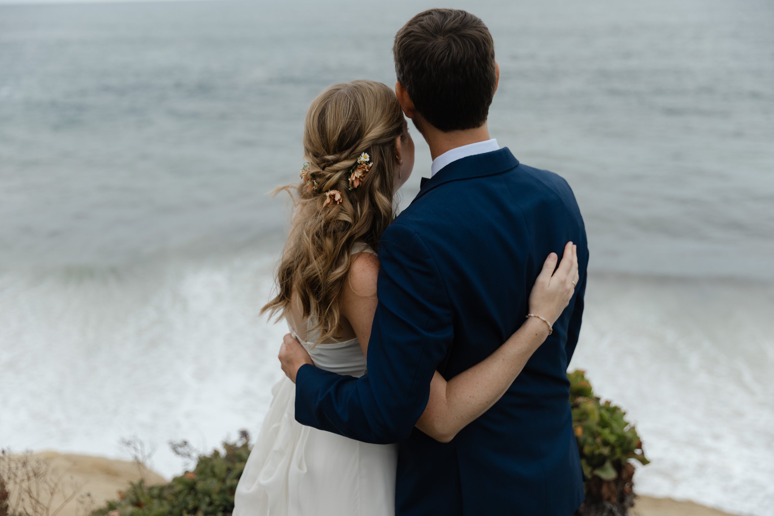 Seth and McKenzie embrace while looking at the ocean at their La Jolla wedding