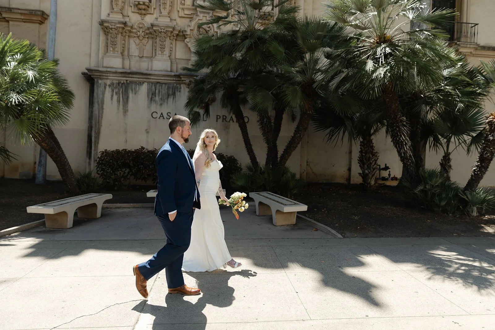 Bride and groom walk through Balboa Park in the morning light.