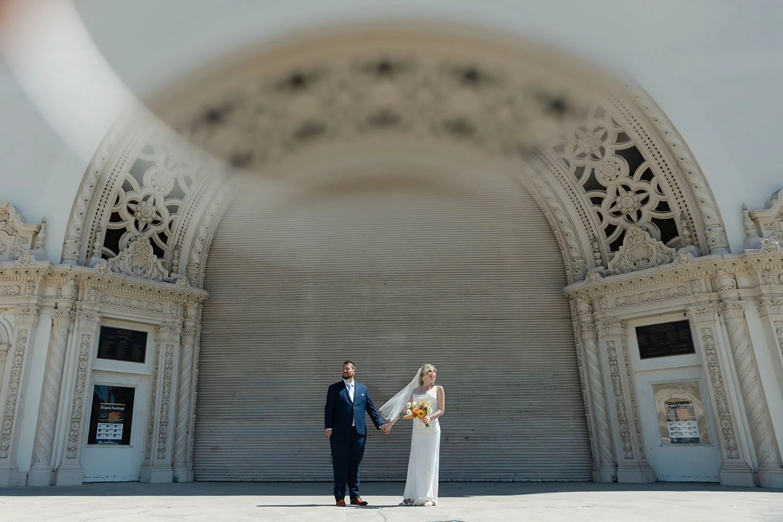 Bride and groom standing in front of the outdoors organ at Balboa Park.