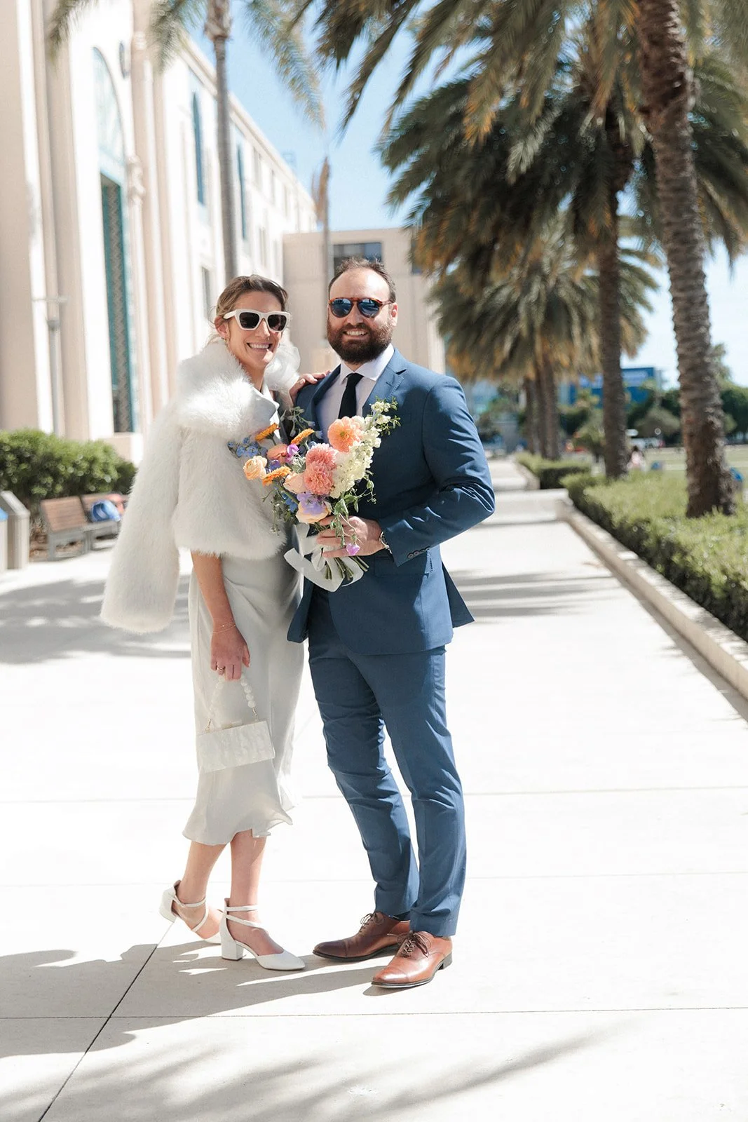 Couple stands smiling for photos after their San Diego Courthouse wedding ceremony.