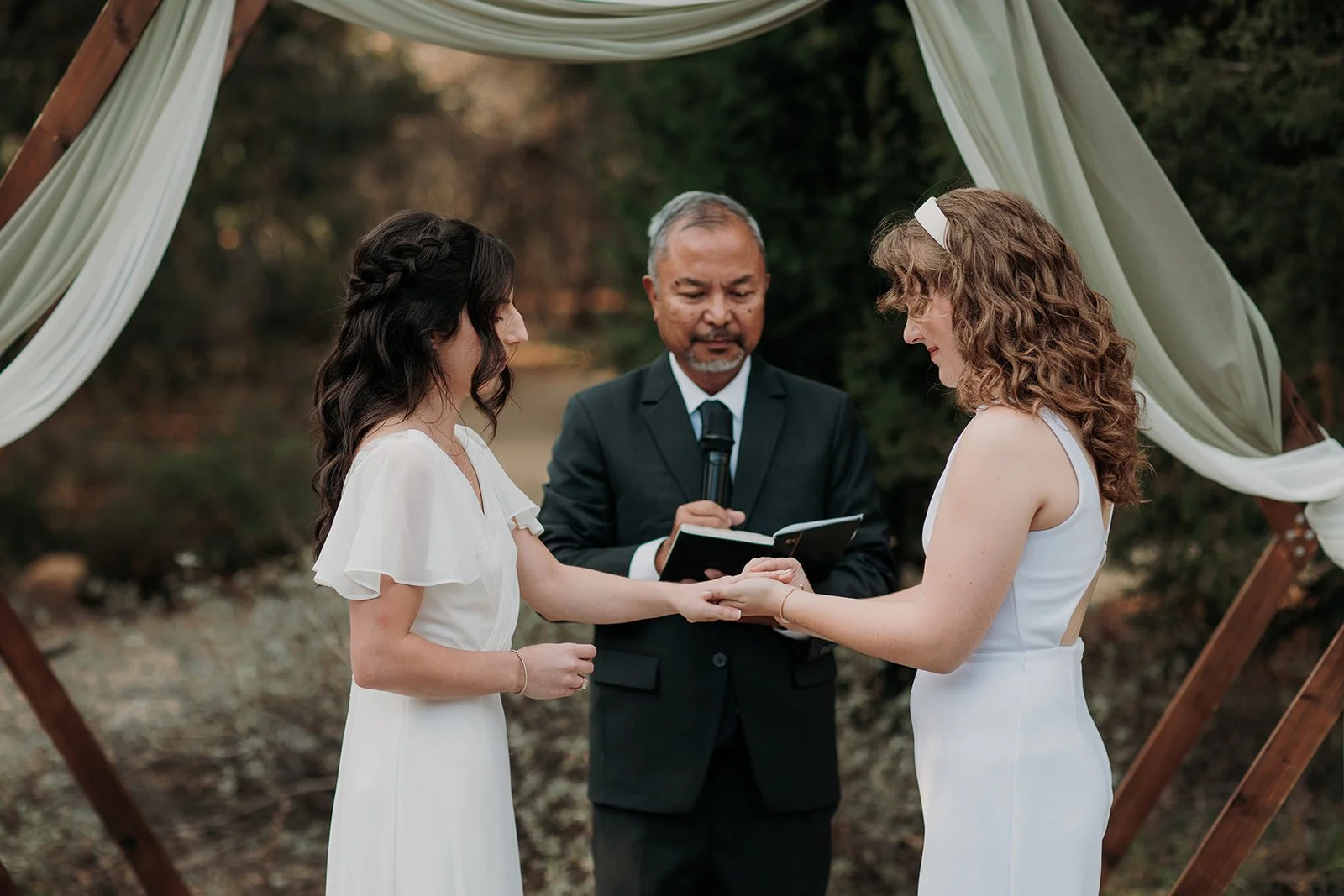 Two brides exchange rings during at their San Diego wedding ceremony at Martin Johnson House.
