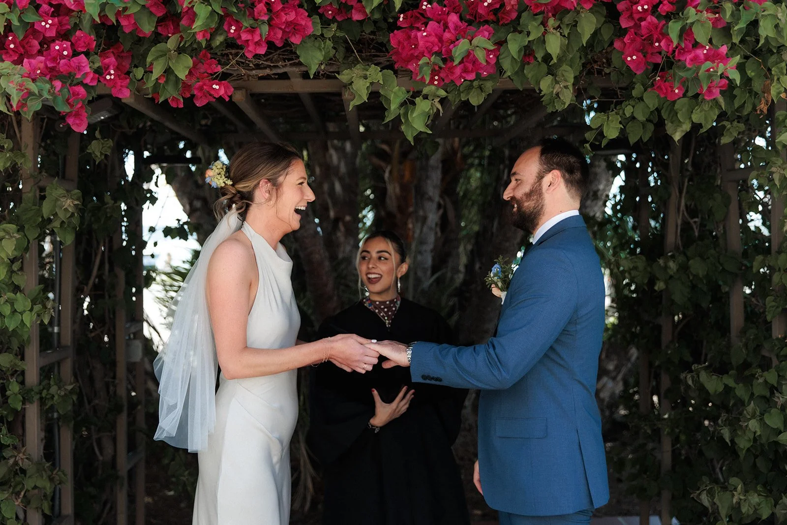 Bride laughs while putting ring on a groom during their San Diego courthouse wedding cremony.