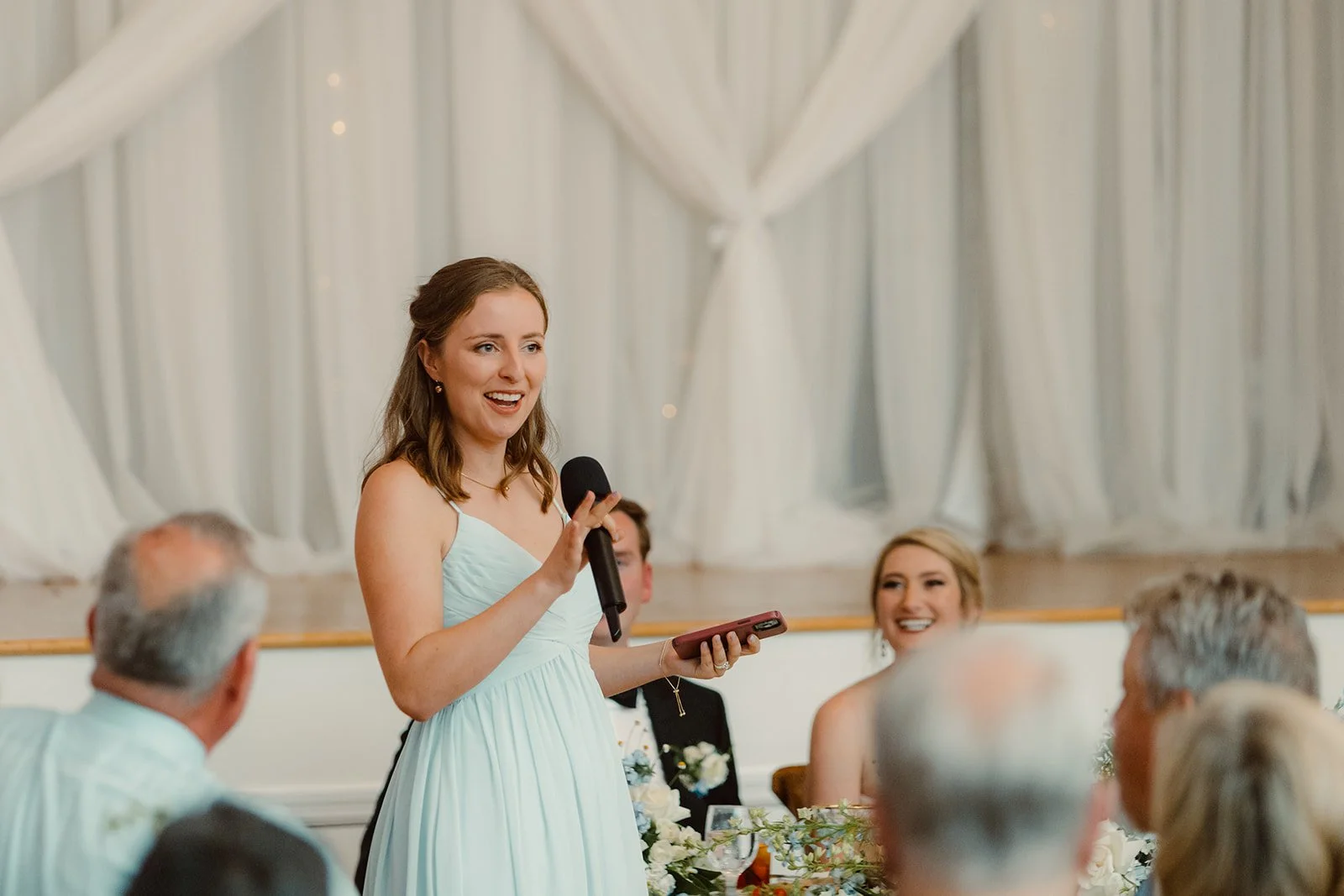 Bridesmaid smiles and stands to give a wedding toast at Cuvier Club in La Jolla.