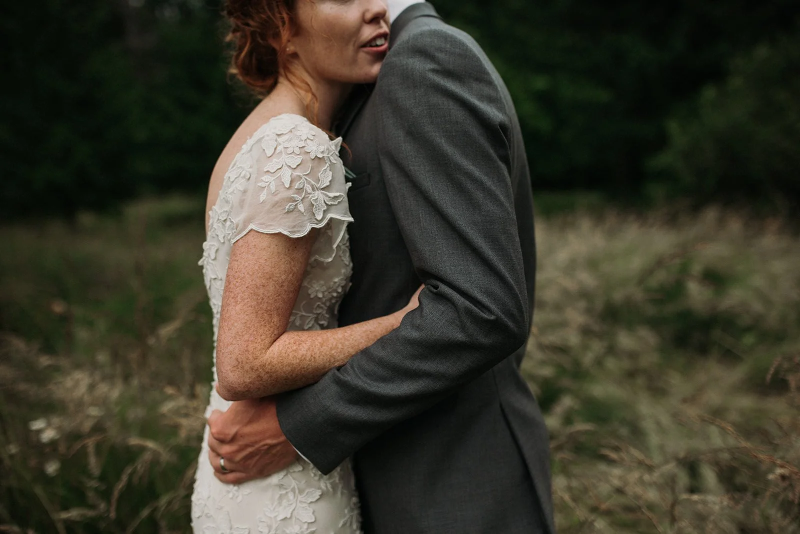 Bride hugs her groom during a quiet moment in a grassy field for their San Diego wedding.