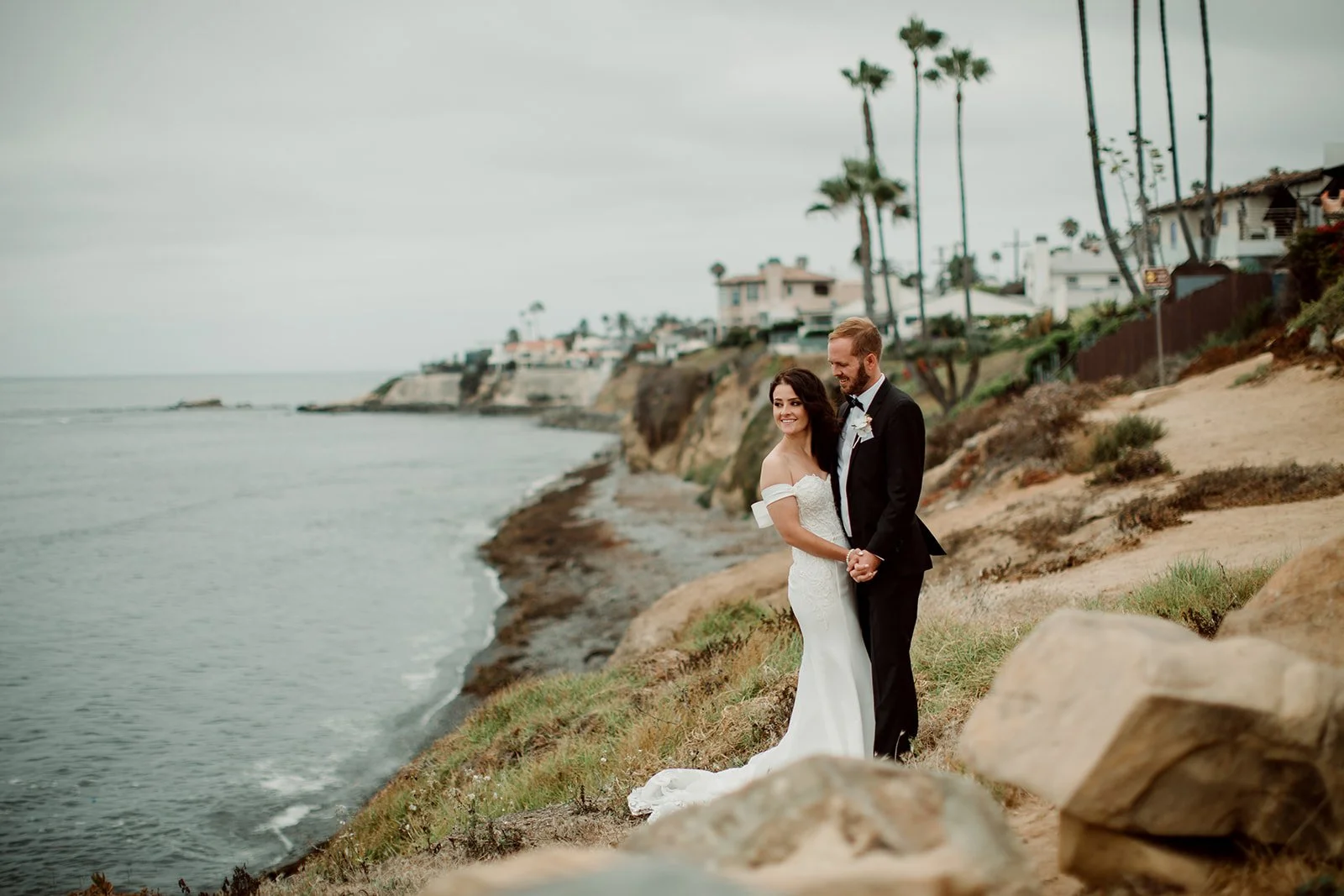 Couple embraces on San Diego beach for their wedding photos.