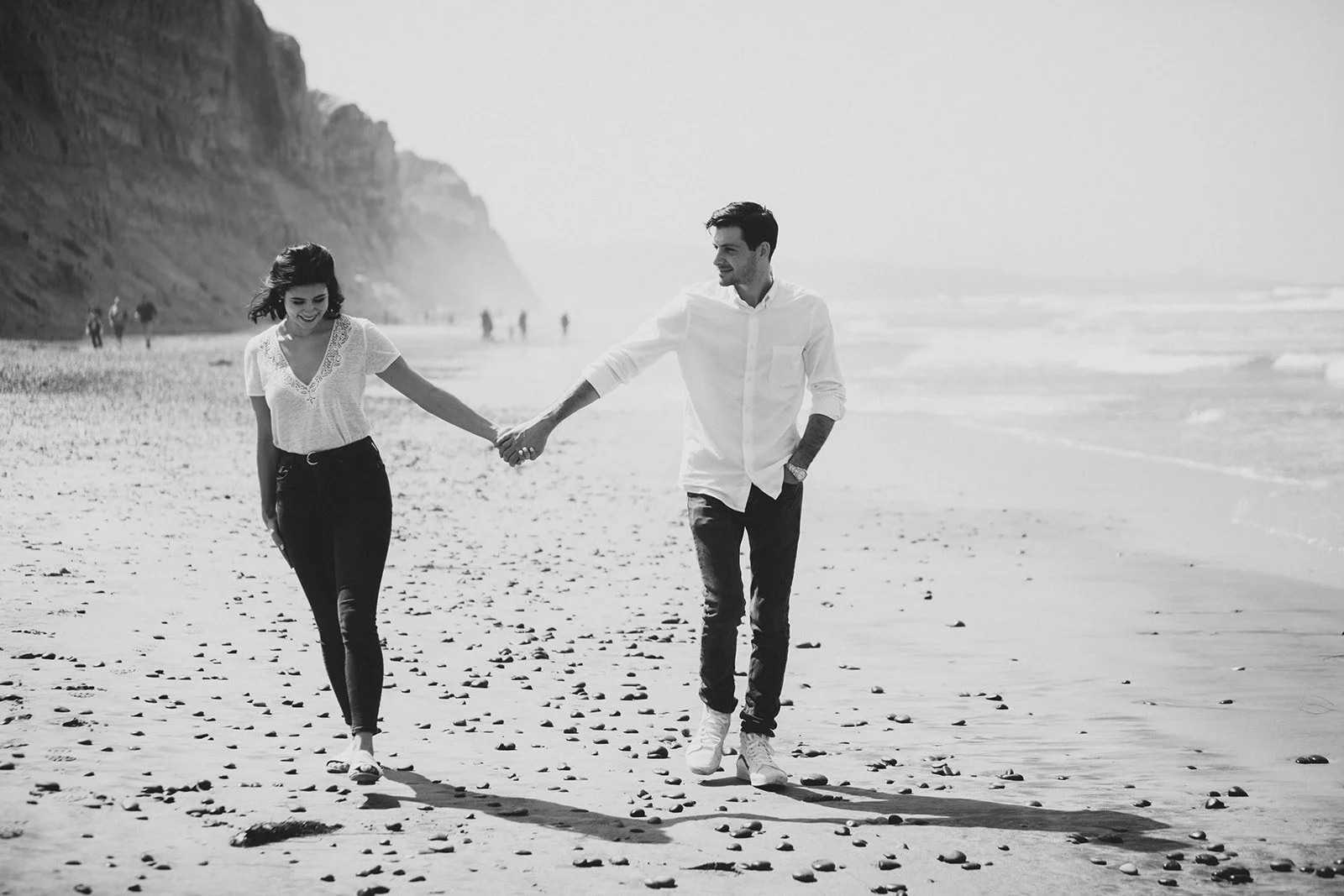 Couple walks hand in hand at Torrey Pines beach after he proposed to her.