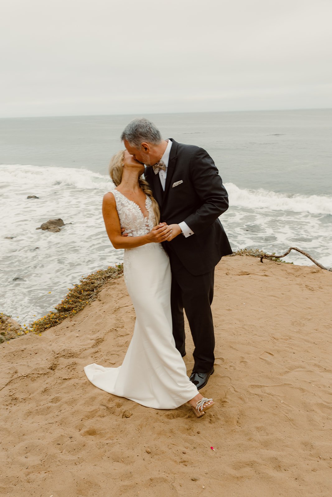 A couple kisses on San Diego coast for their wedding.